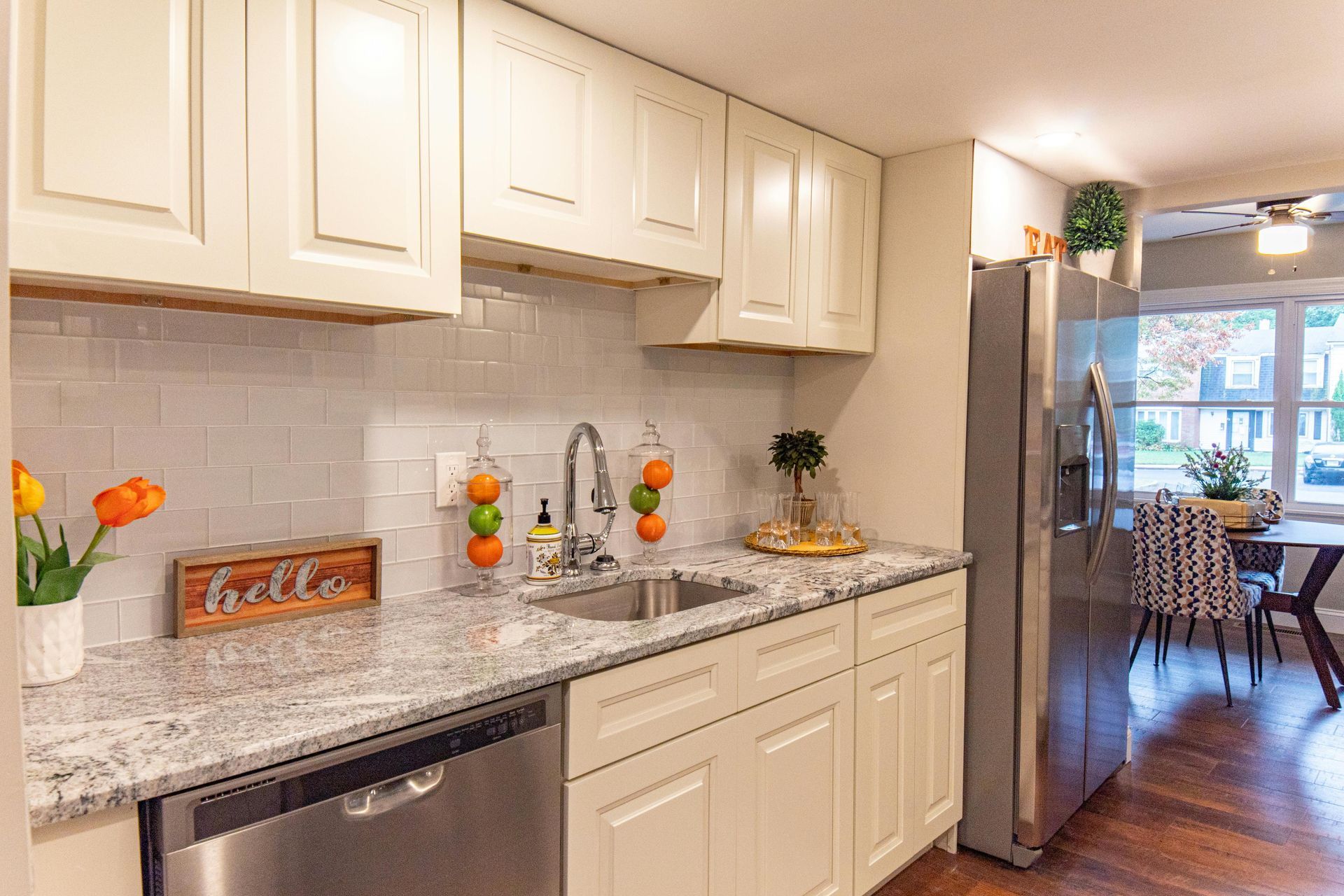 Cream-colored kitchen cabinets with granite countertops, stainless steel appliances, and a view into a dining room.