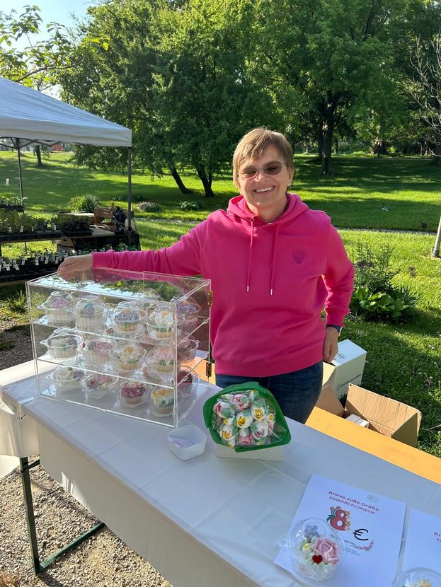 Zwei Personen in weißen T-Shirts zünden Kerzen auf einem kleinen Kuchen vor einem Ballon mit der Zahl Eins an.