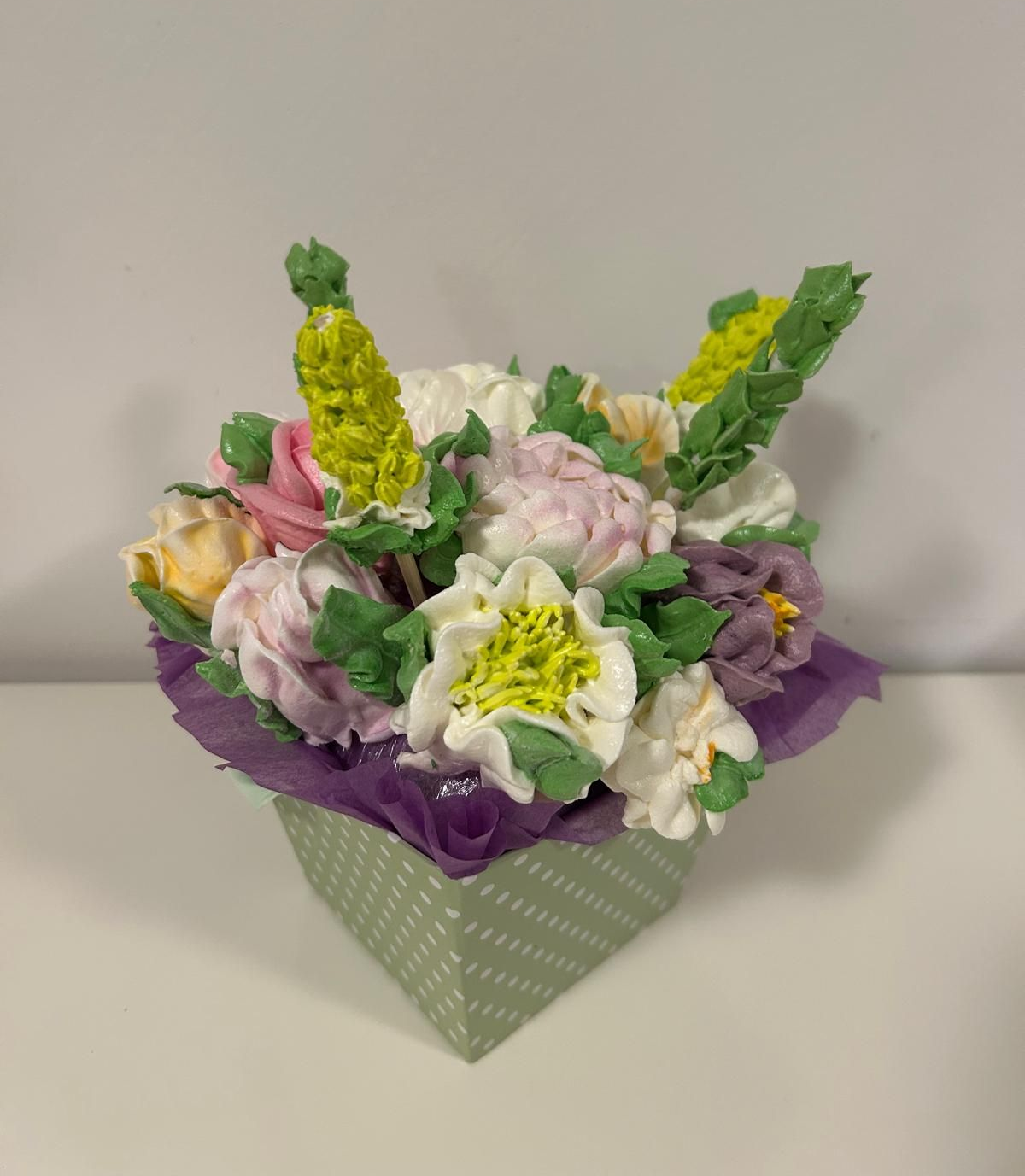 Pastellfarbener Papierblumenstrauß in einer grau gemusterten Schachtel mit lila Seidenpapier