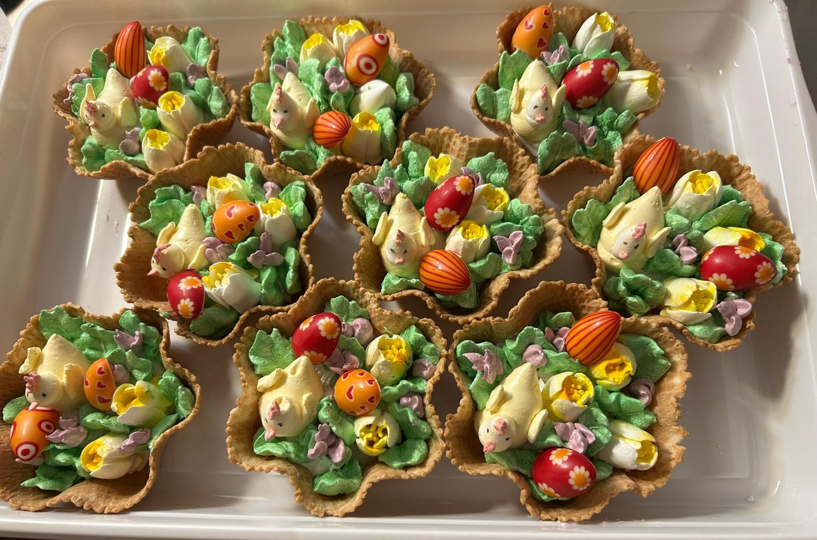 Verschiedene dekorierte, blumenförmige Dessertbecher mit bunten Süßigkeiten und Früchten auf einem Tablett