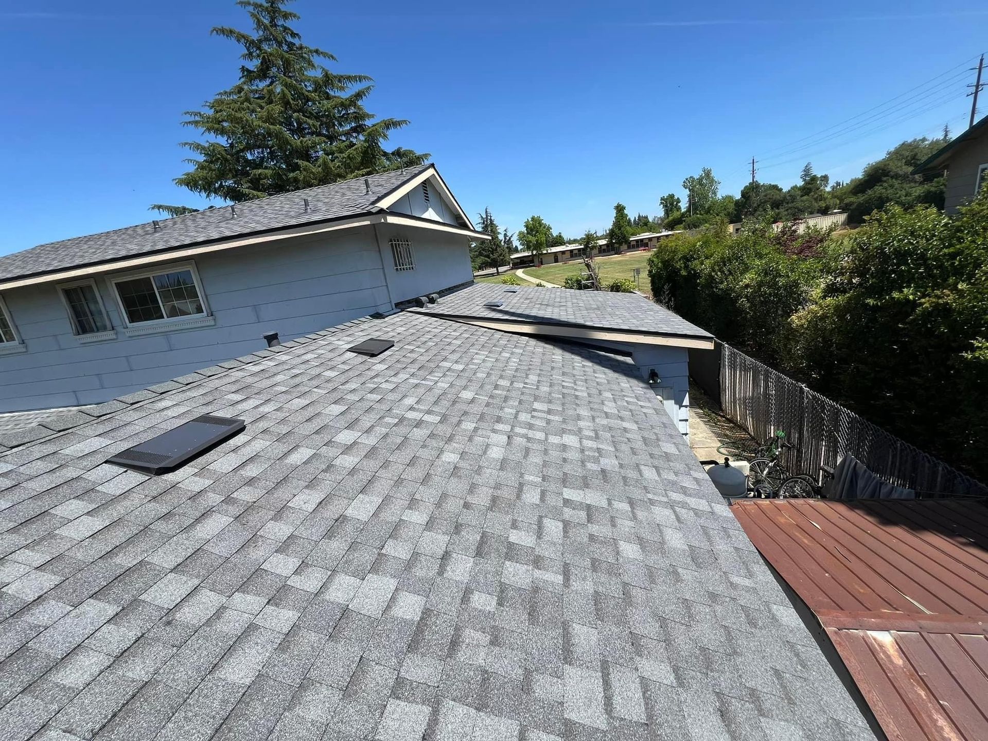 A roof with a lot of shingles on it and a fence in the background.