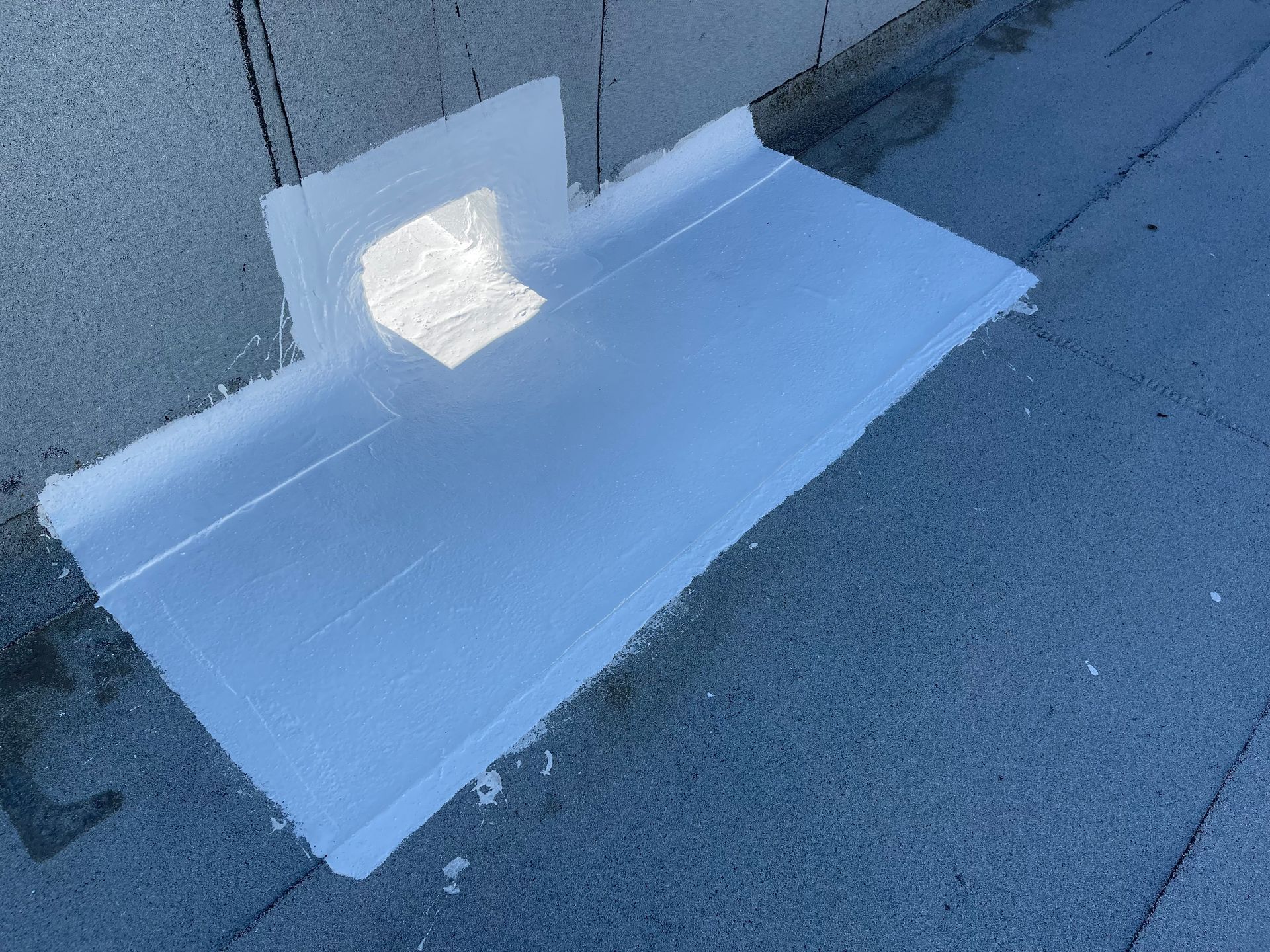 A piece of ice is sitting on the ground next to a wall.