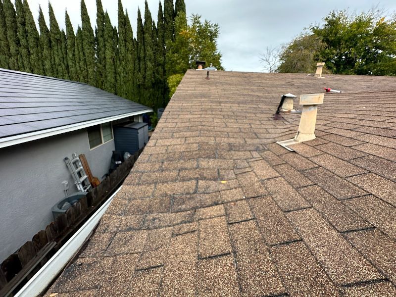 The roof of a house with a ladder and gutter on it.