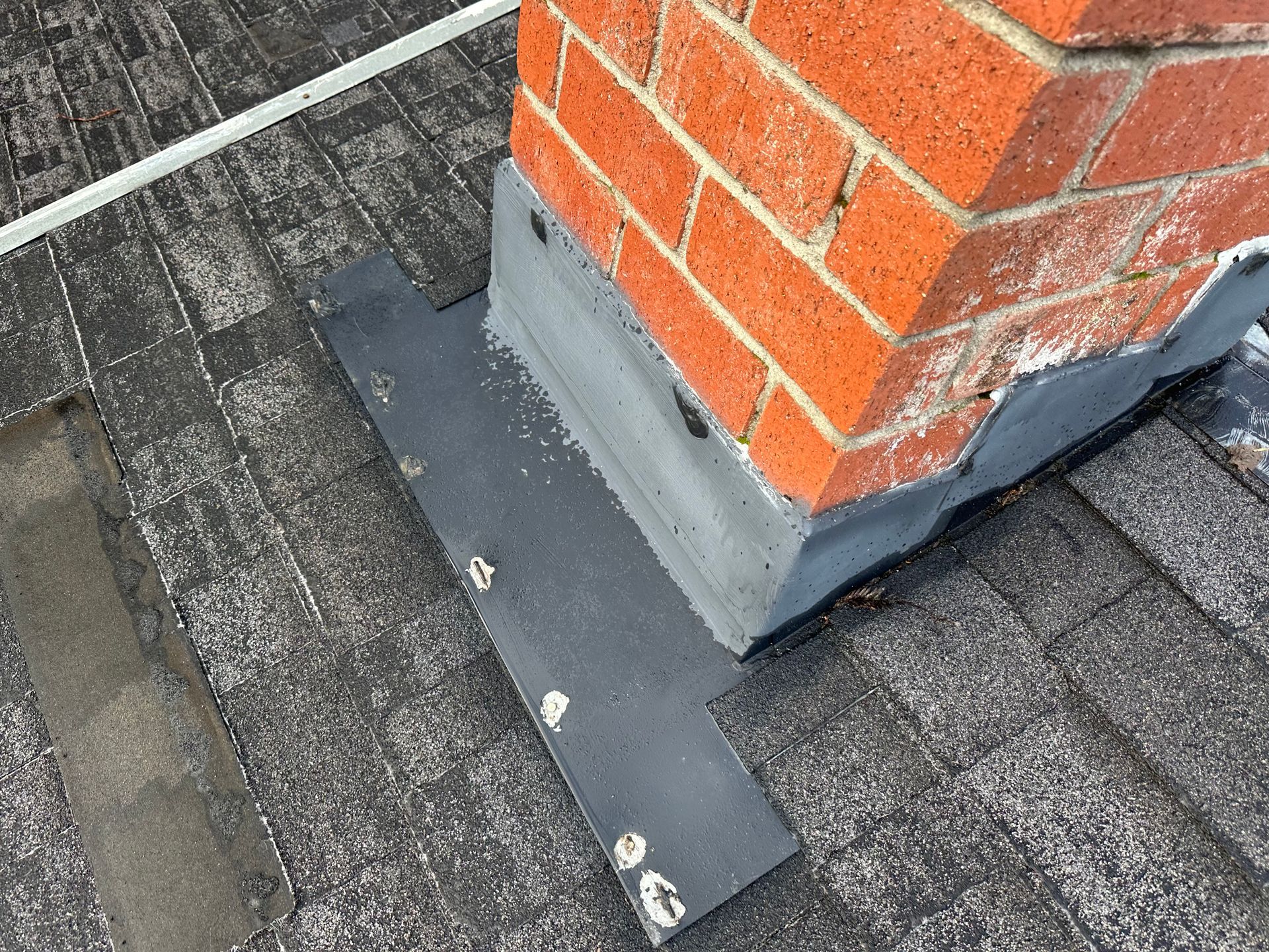 A brick chimney is sitting on top of a roof.