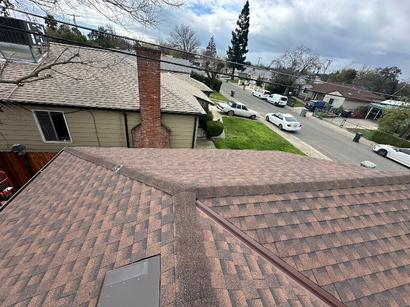 A rooftop view of a house with a chimney and a street in the background.