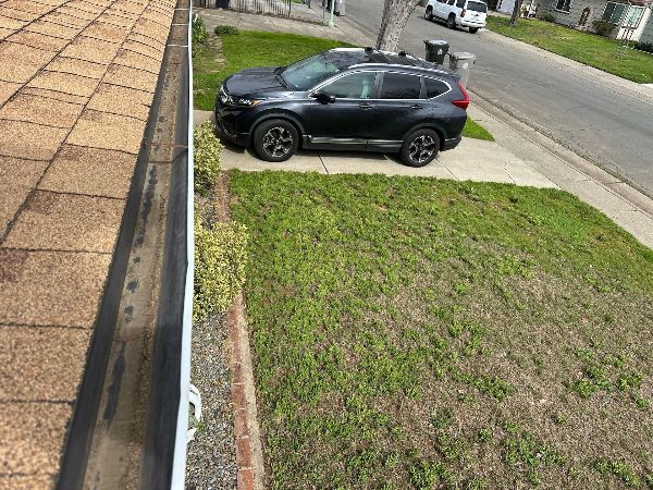 A black suv is parked in a driveway next to a gutter.