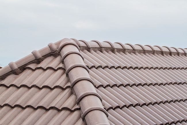 A man is installing tiles on a roof.