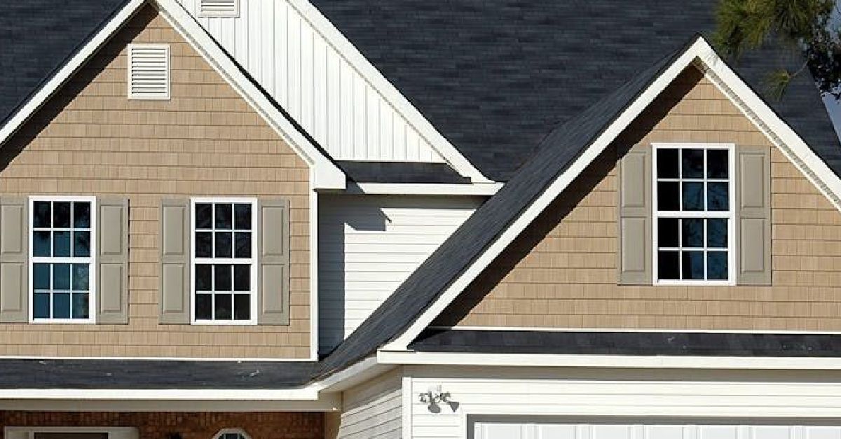 A house with a black roof and brown siding has a garage.