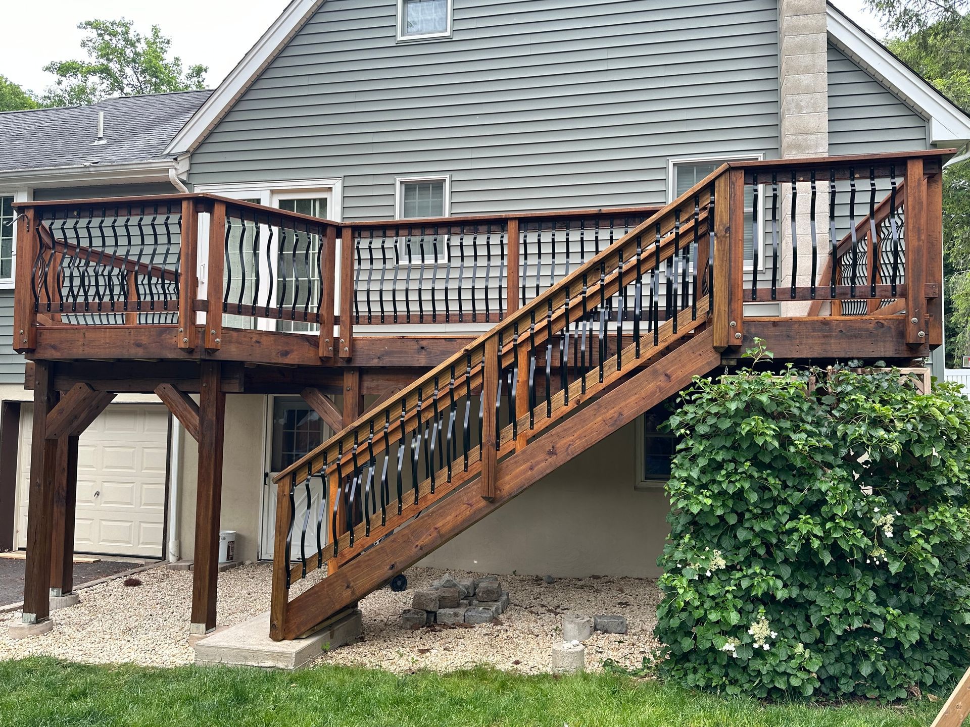A wooden deck with stairs leading up to it is in front of a house.
