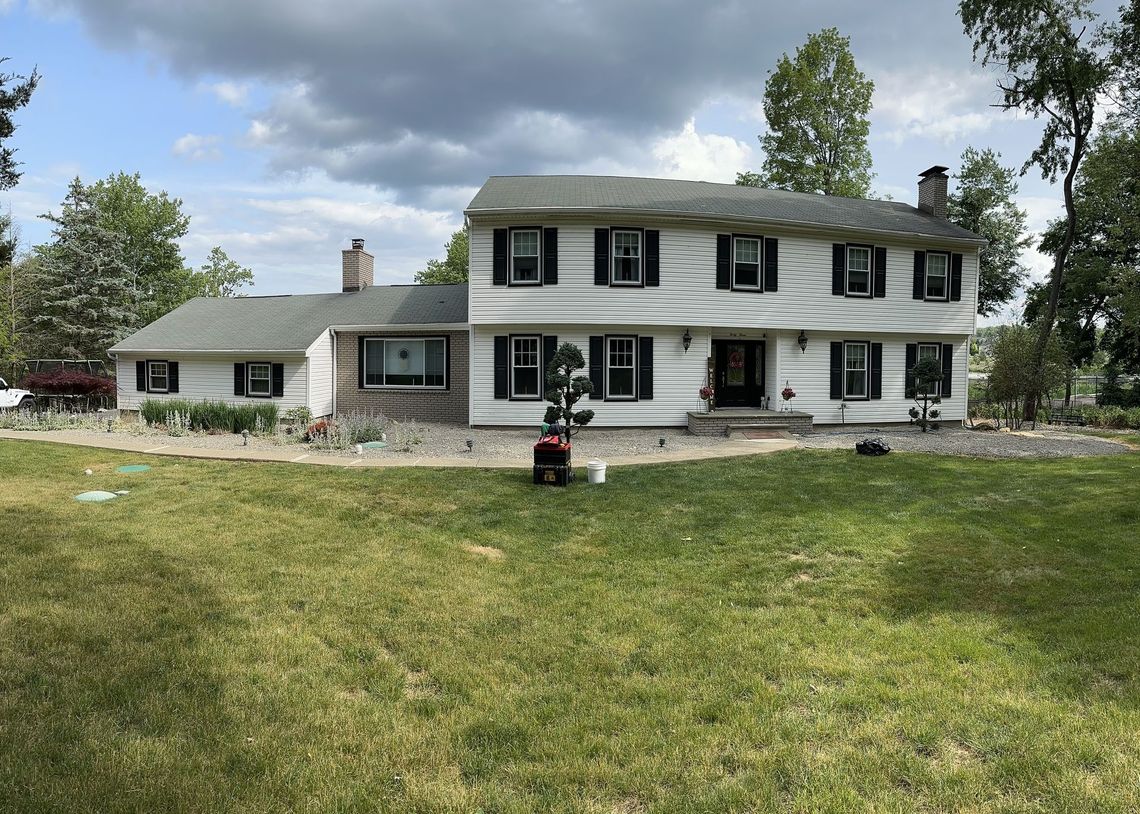 A large white house with a lawn mower in front of it.