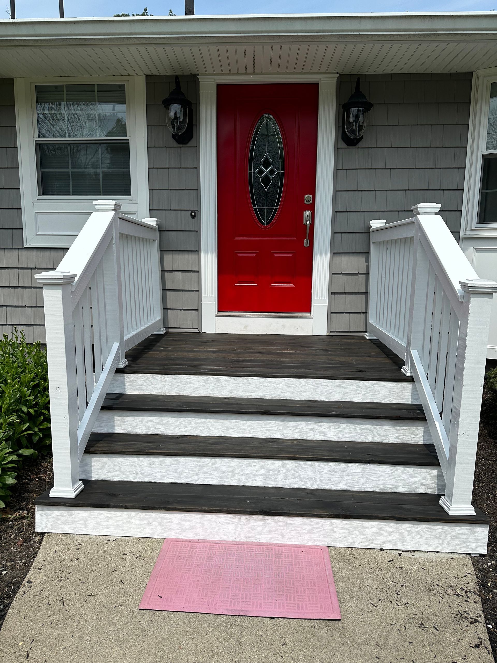 The front of a house with a red door and white railing