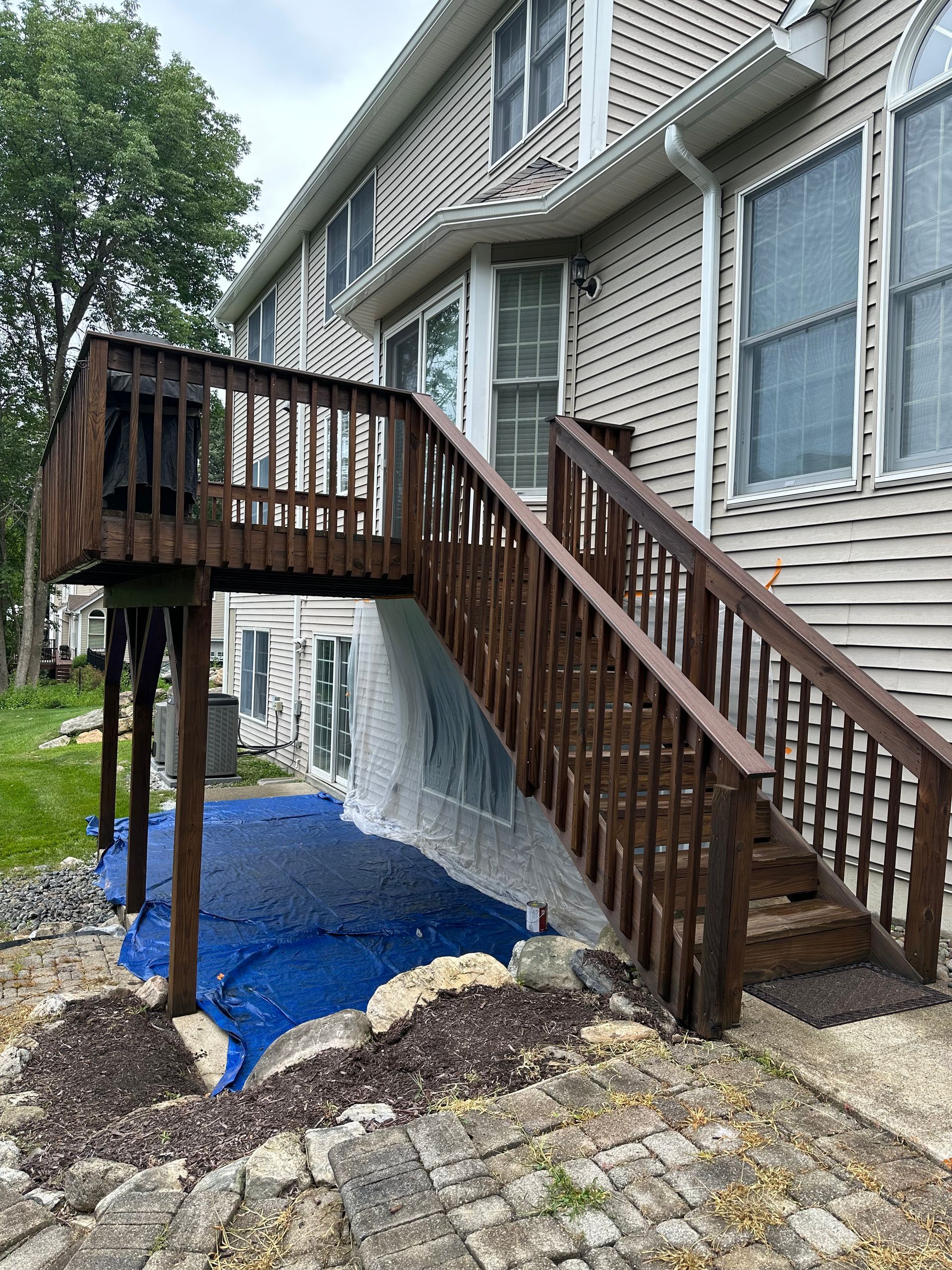 A wooden deck with stairs leading up to the back of a house.