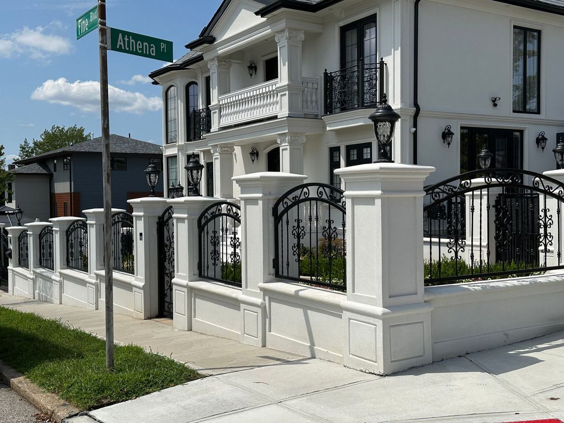 A large white house with a fence and a street sign that says alterra