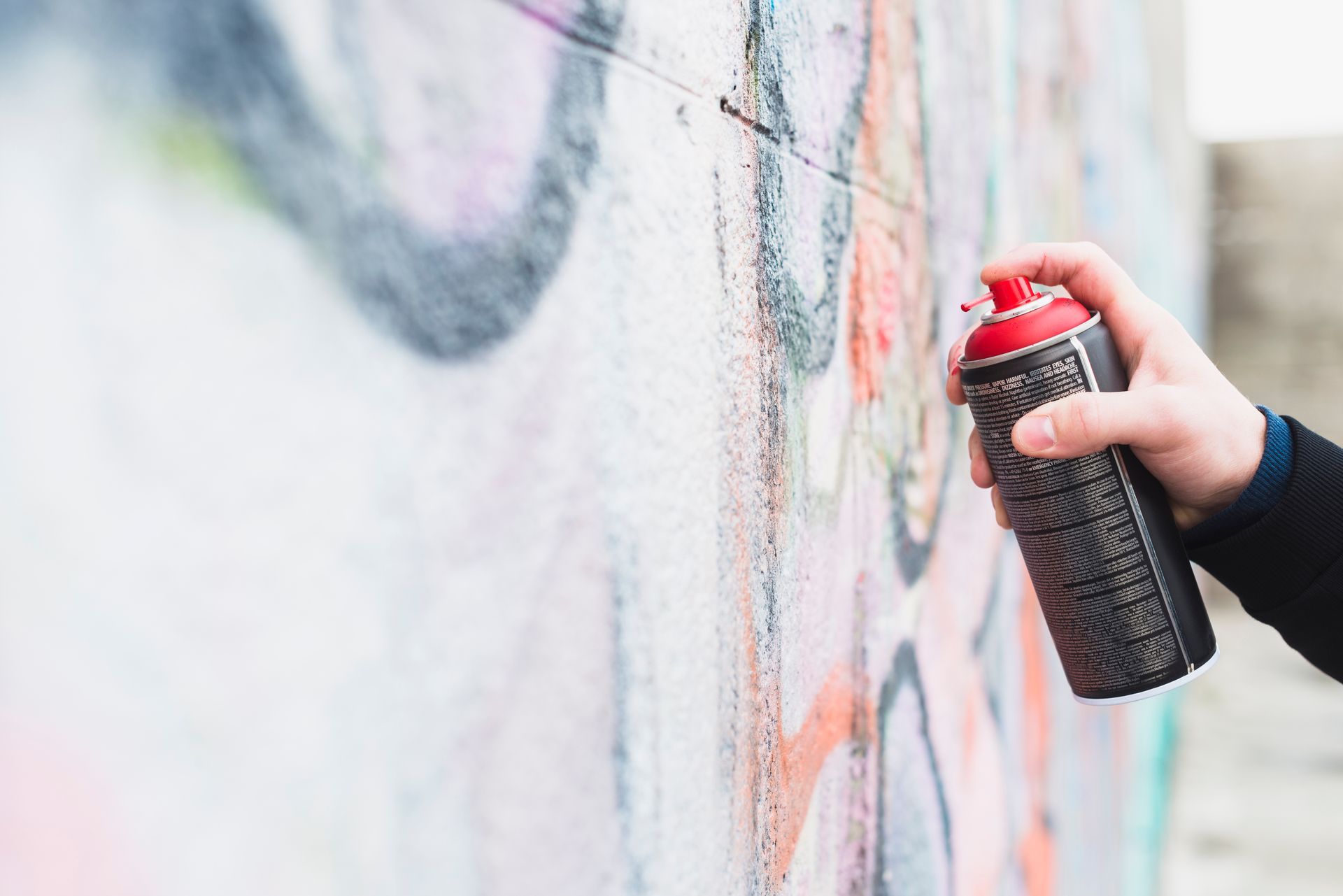 A person is spray painting graffiti on a wall.