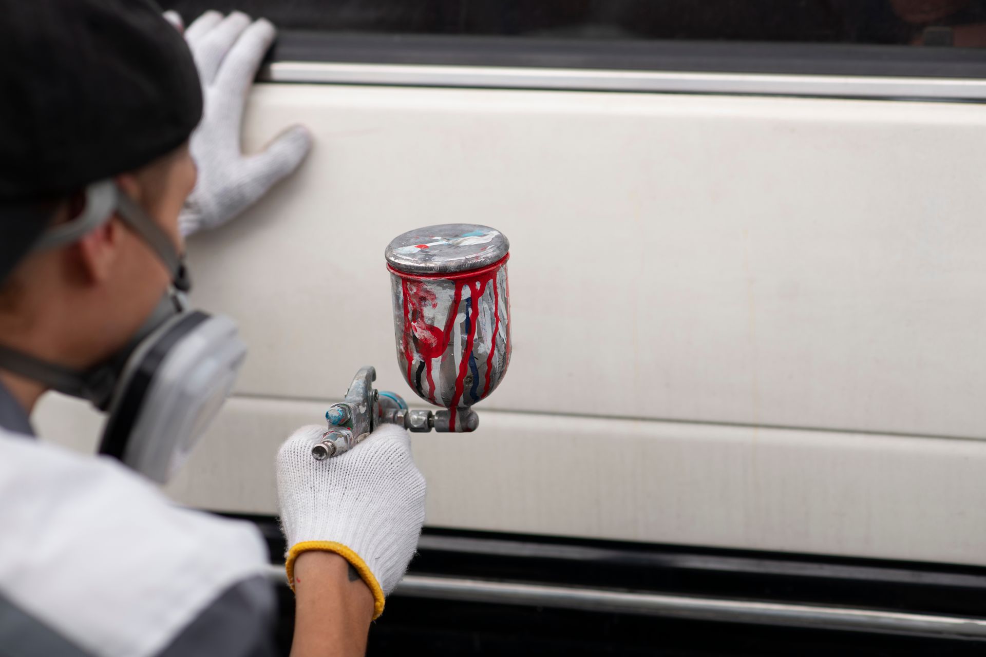 A man is painting a car with an airbrush.