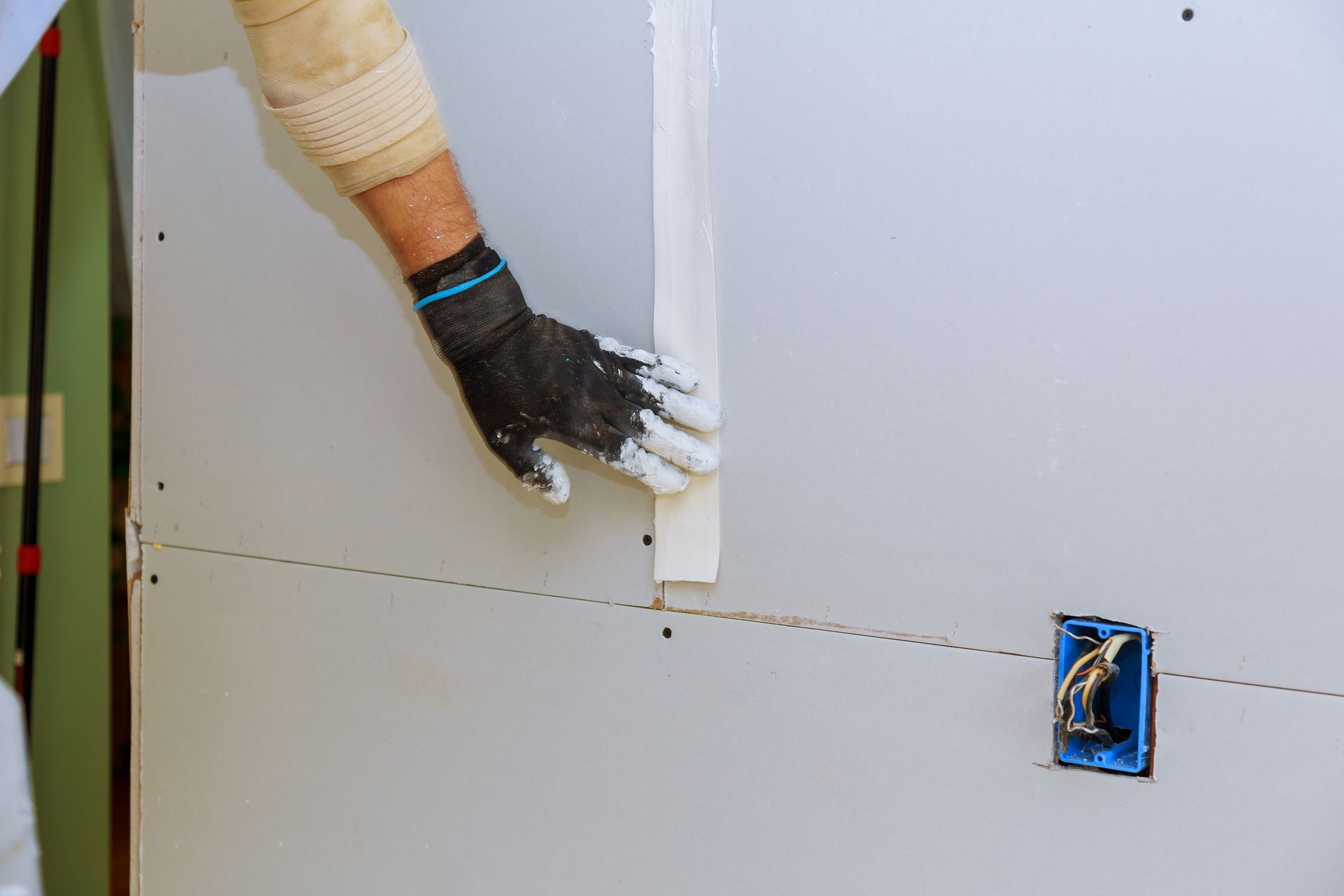 A person is plastering a wall with a trowel.