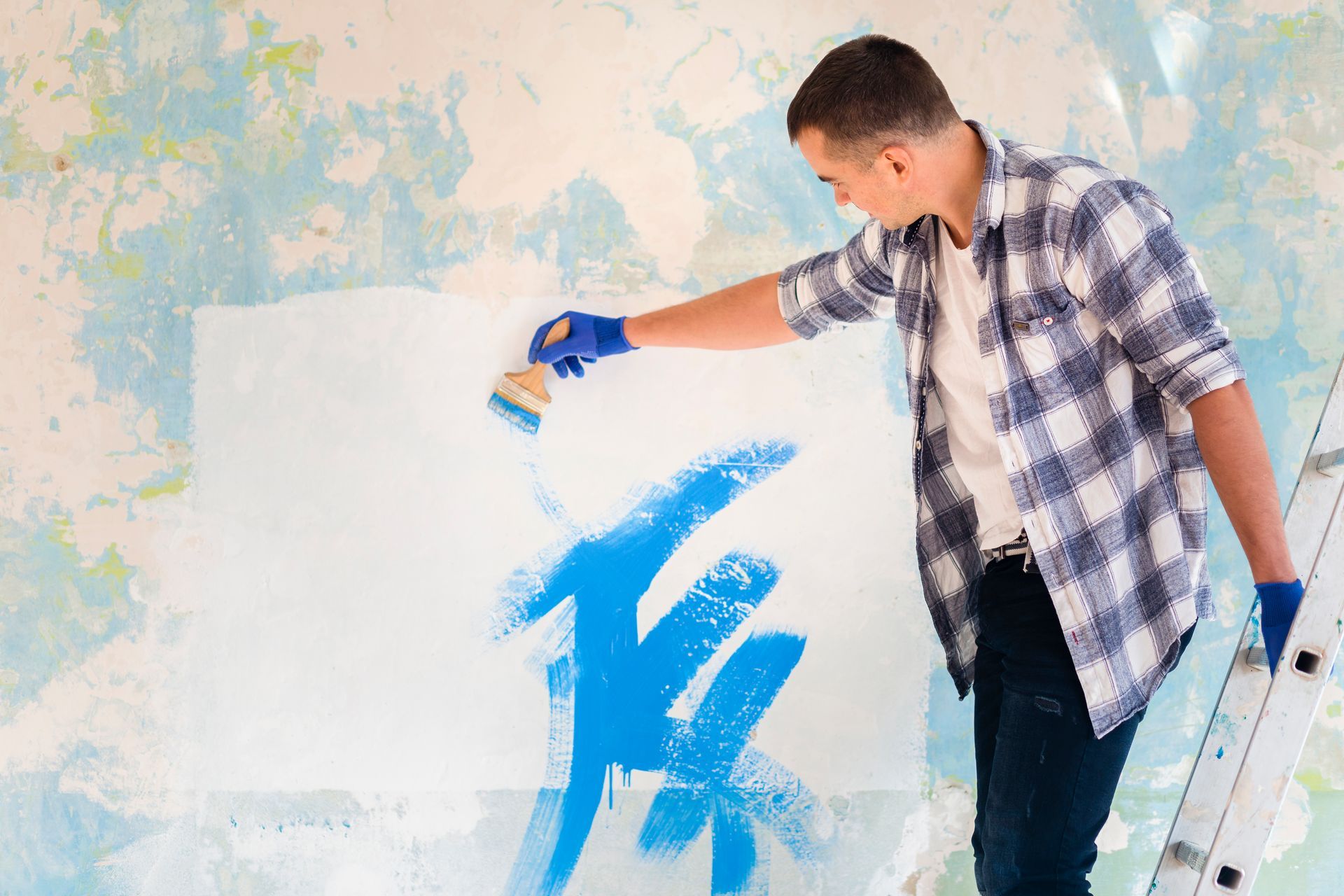 A man is painting a wall with a blue brush.