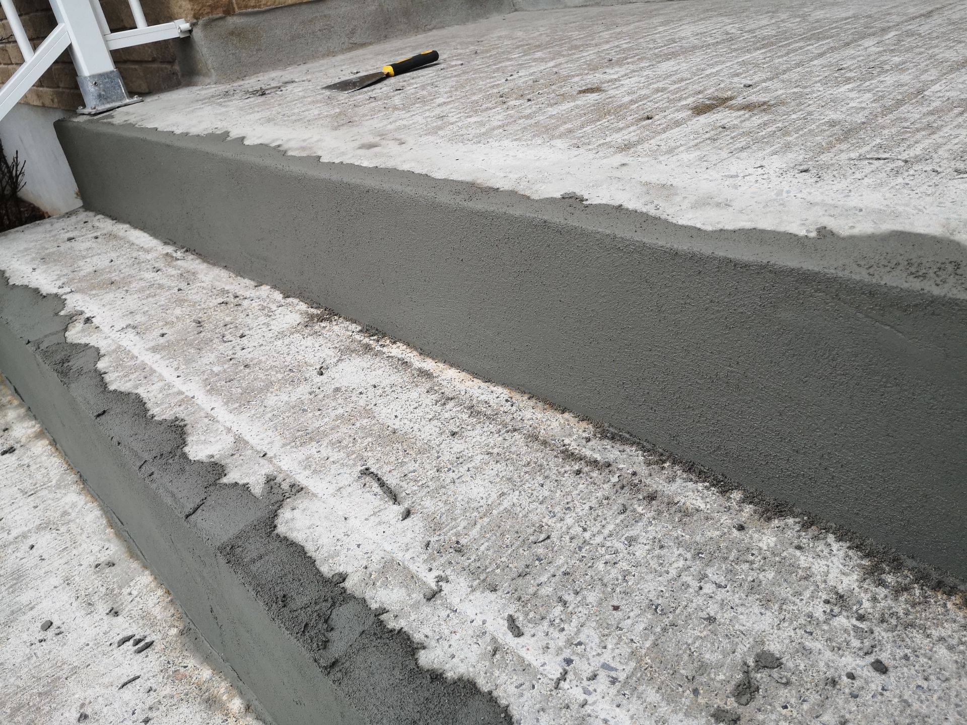 Concrete steps being repaired, with fresh gray cement applied to edges.