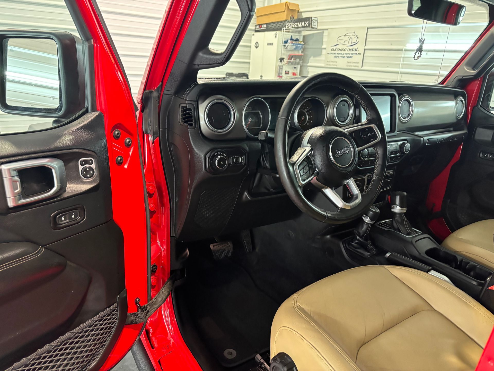 The interior of a red jeep wrangler with the door open.