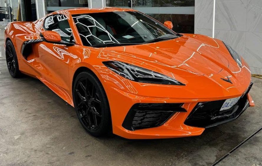 An orange sports car is parked in front of a building.