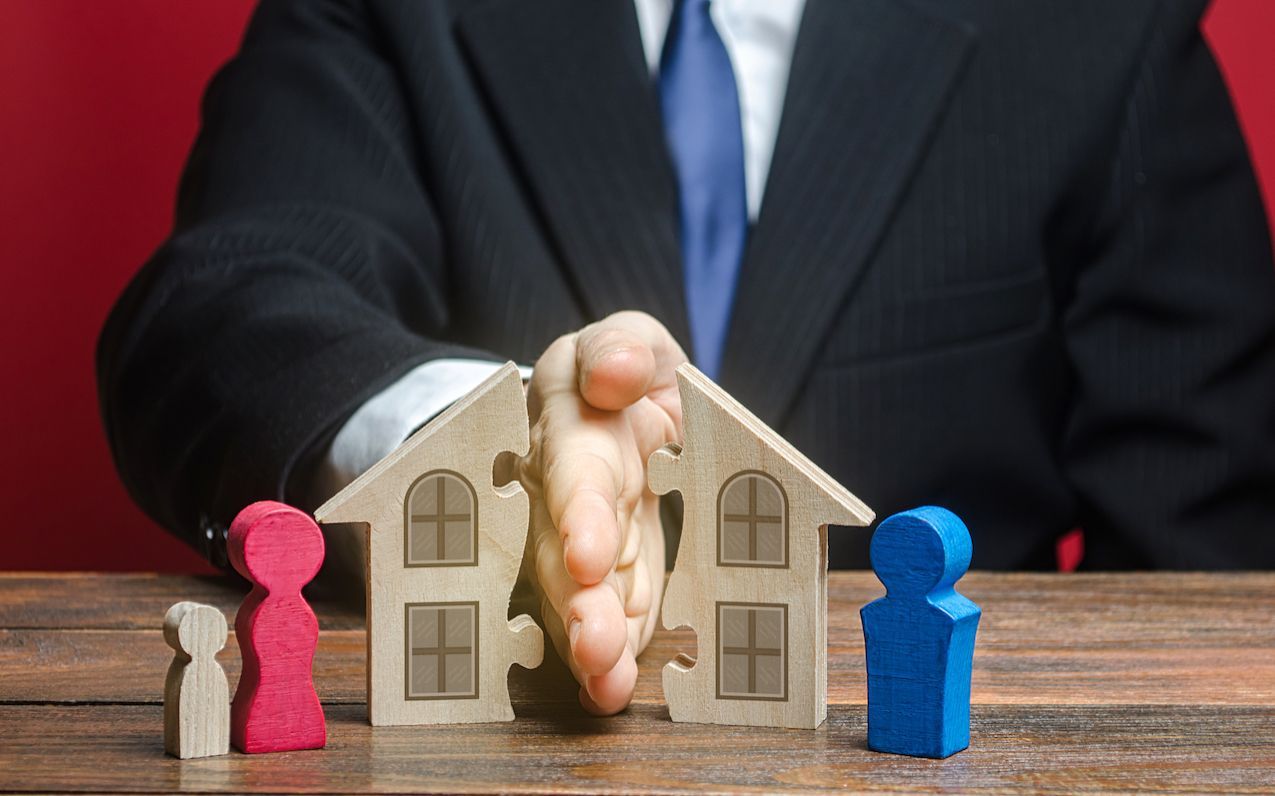 A man in a suit holds a puzzle piece depicting a house and family, symbolising a property dispute