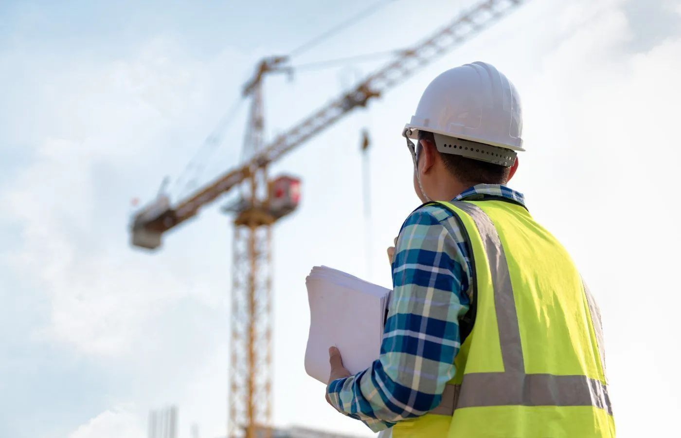 Construction professional reviewing plans for a building insurance claim on-site