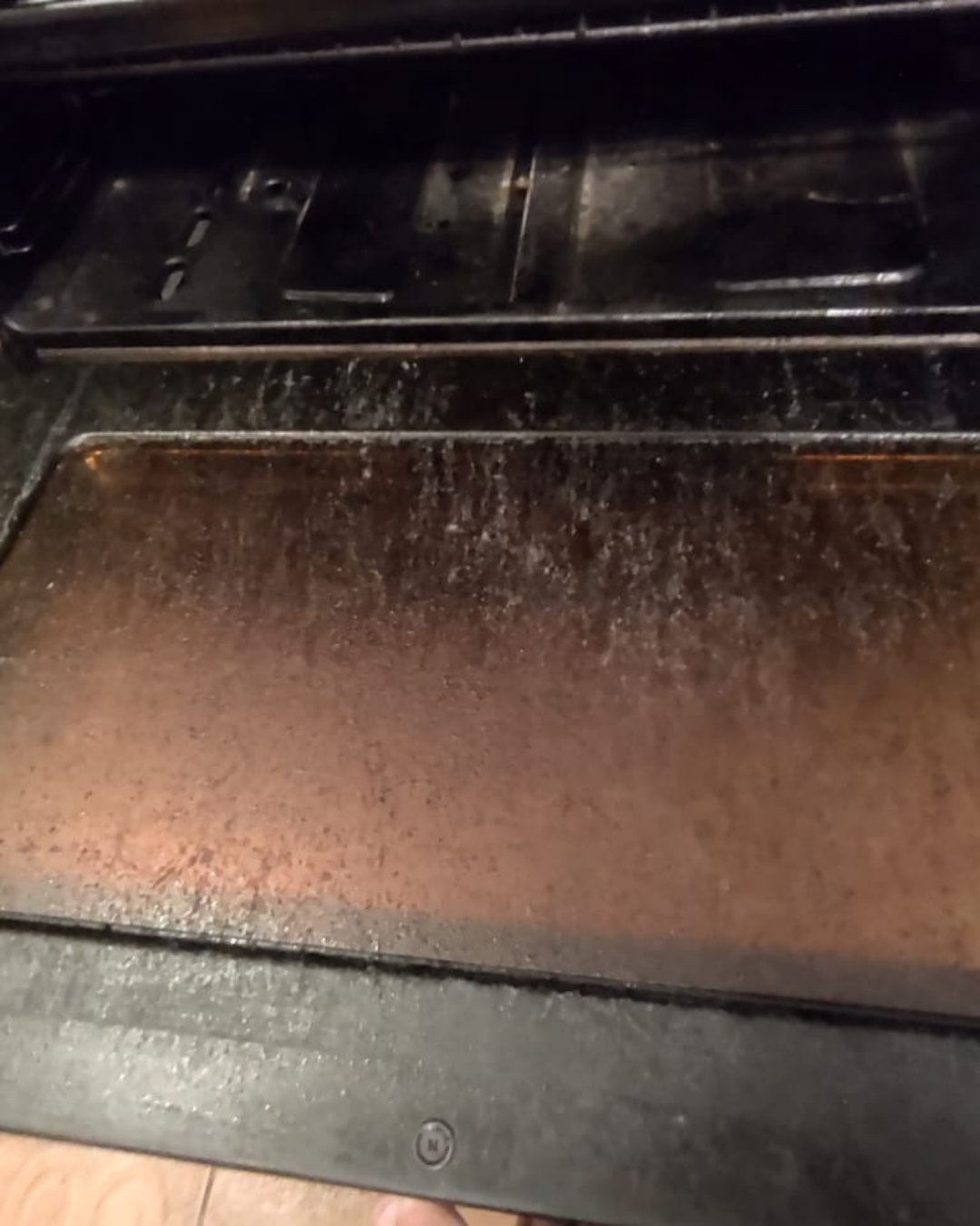 Interior del horno sucio, con residuos marrones y negros en la parte inferior.