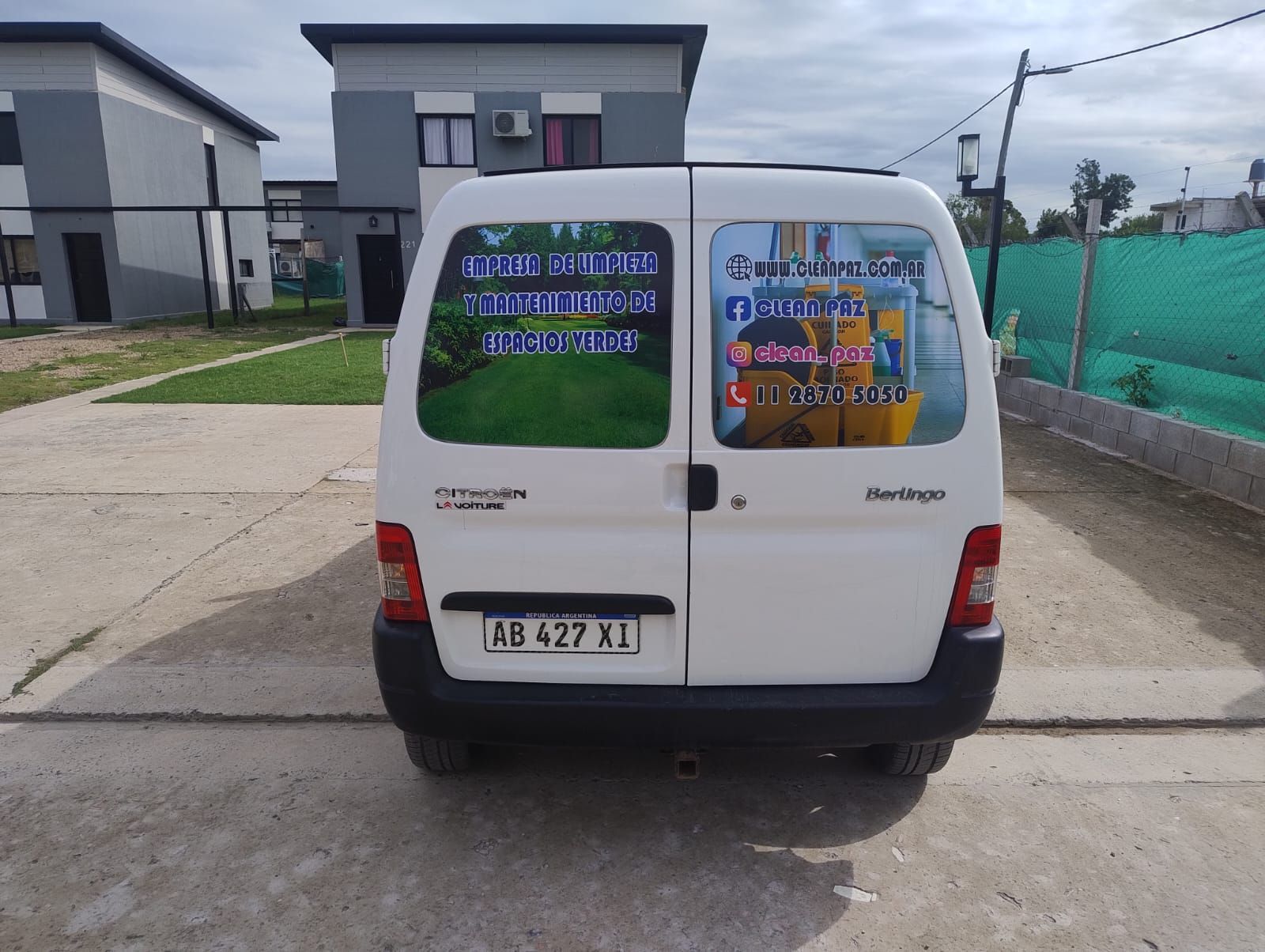 Furgoneta comercial de color blanco con logotipos empresariales en las ventanas traseras.