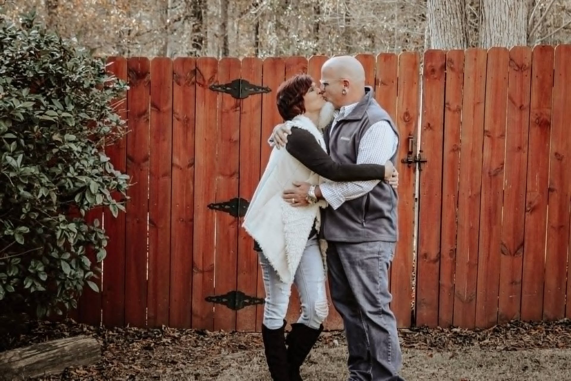 Couple kissing in front of a red wooden fence door – Shine Again Photography couples session in Newnan GA