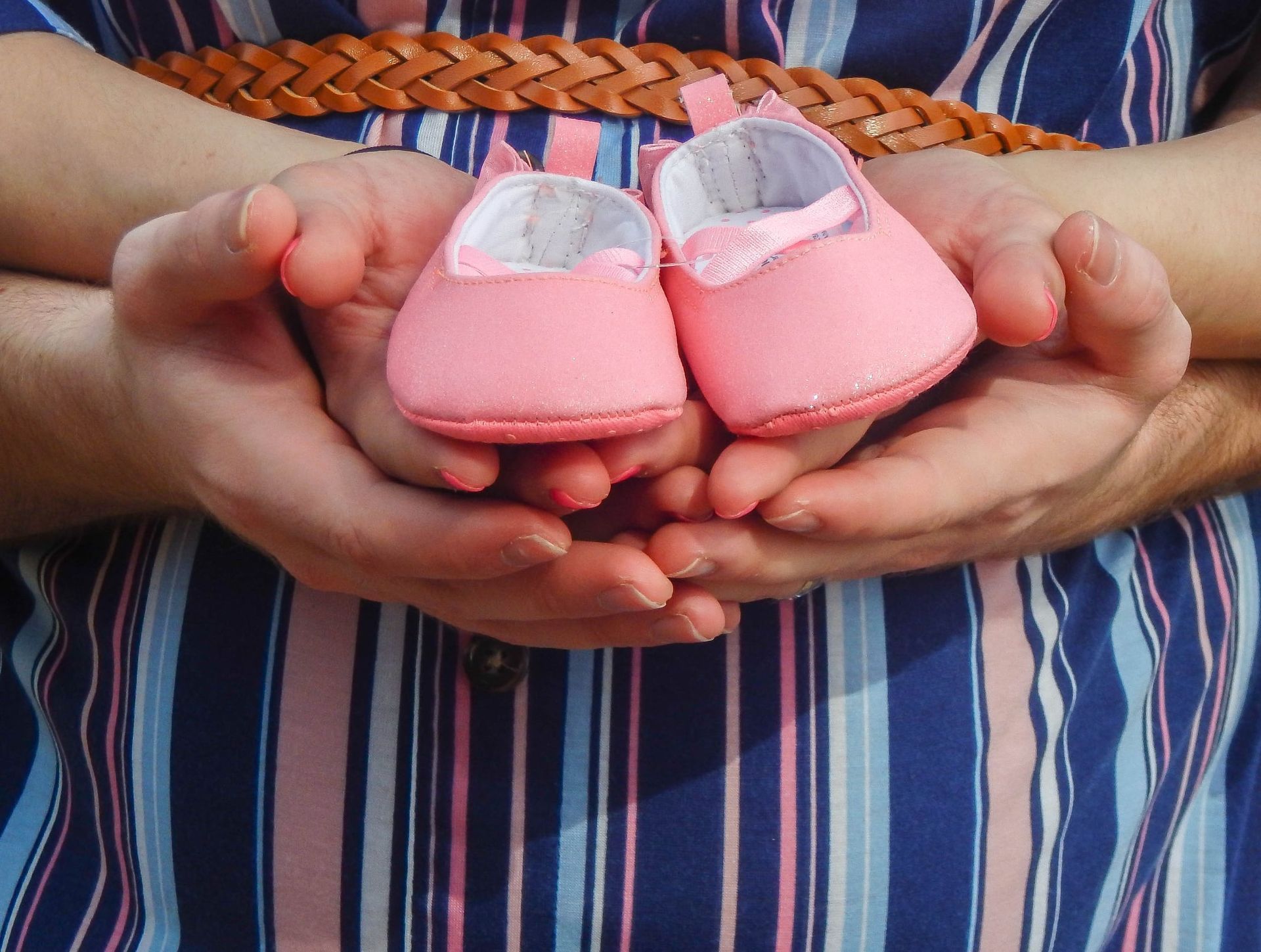 Parents holding tiny pink baby shoes over a baby bump – Shine Again Photography Newnan GA