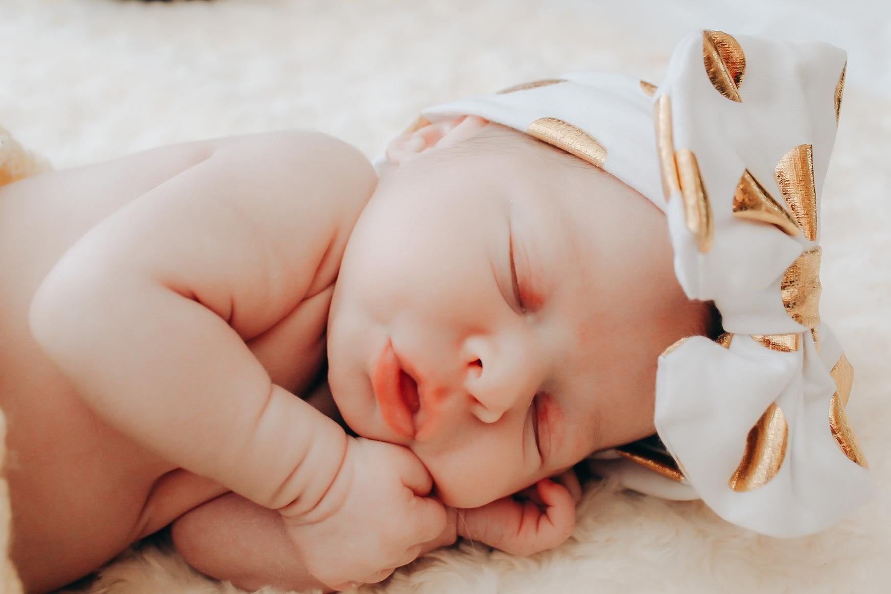 Sleeping newborn baby girl with a large hair bow, Newnan GA newborn photography session.
