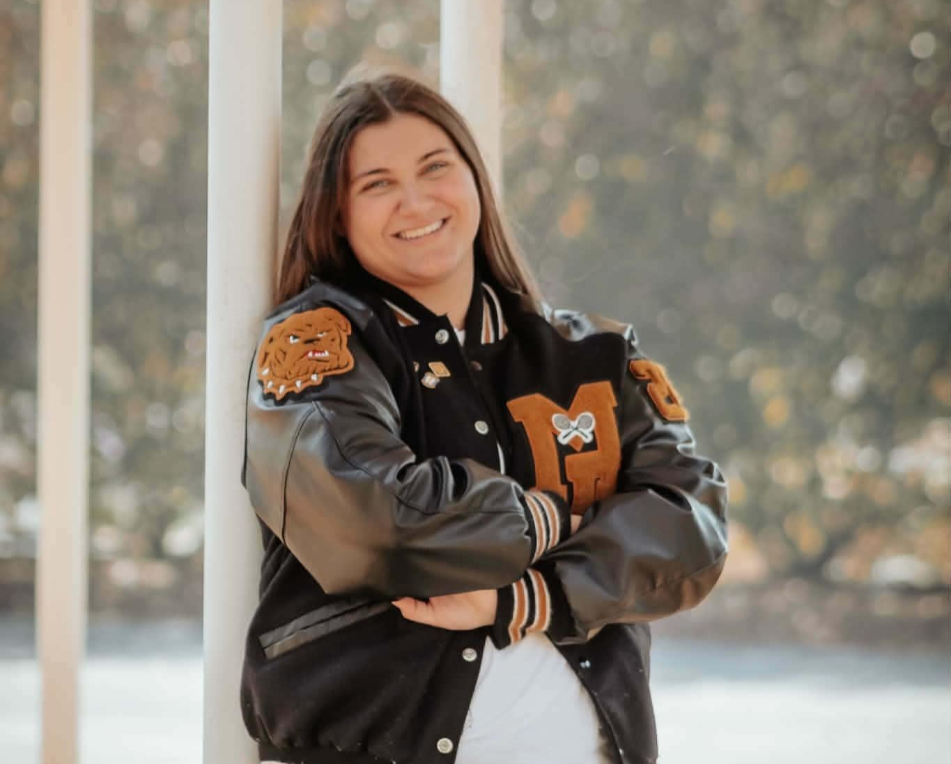 High school senior girl smiling in a custom letterman jacket outdoors – Shine Again Photography Newnan GA