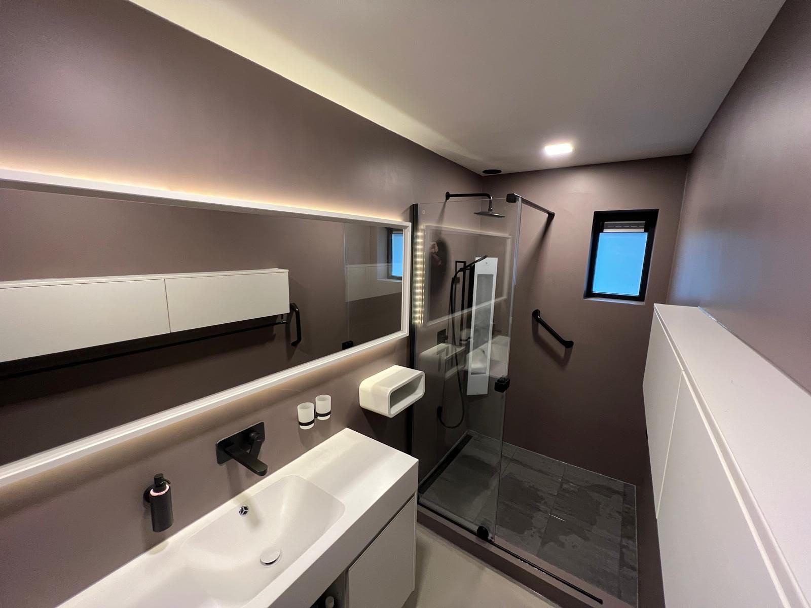 Moderne badkamer met wastafel, spiegel, inloopdouche en donkergrijze muren.