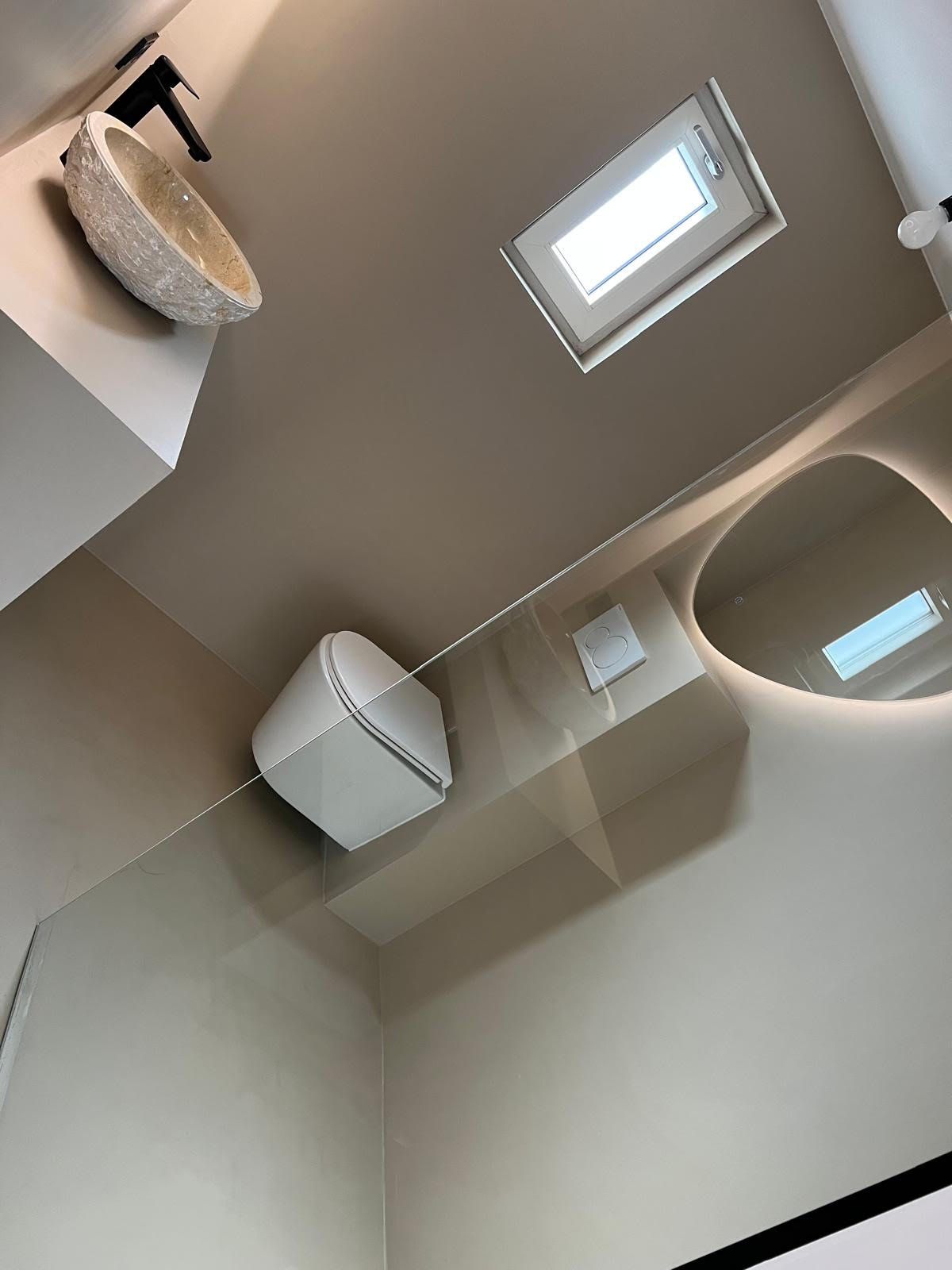 Badkamerplafond met dakraam, wandluidspreker en handdoekrek onder een handdoekdispenser