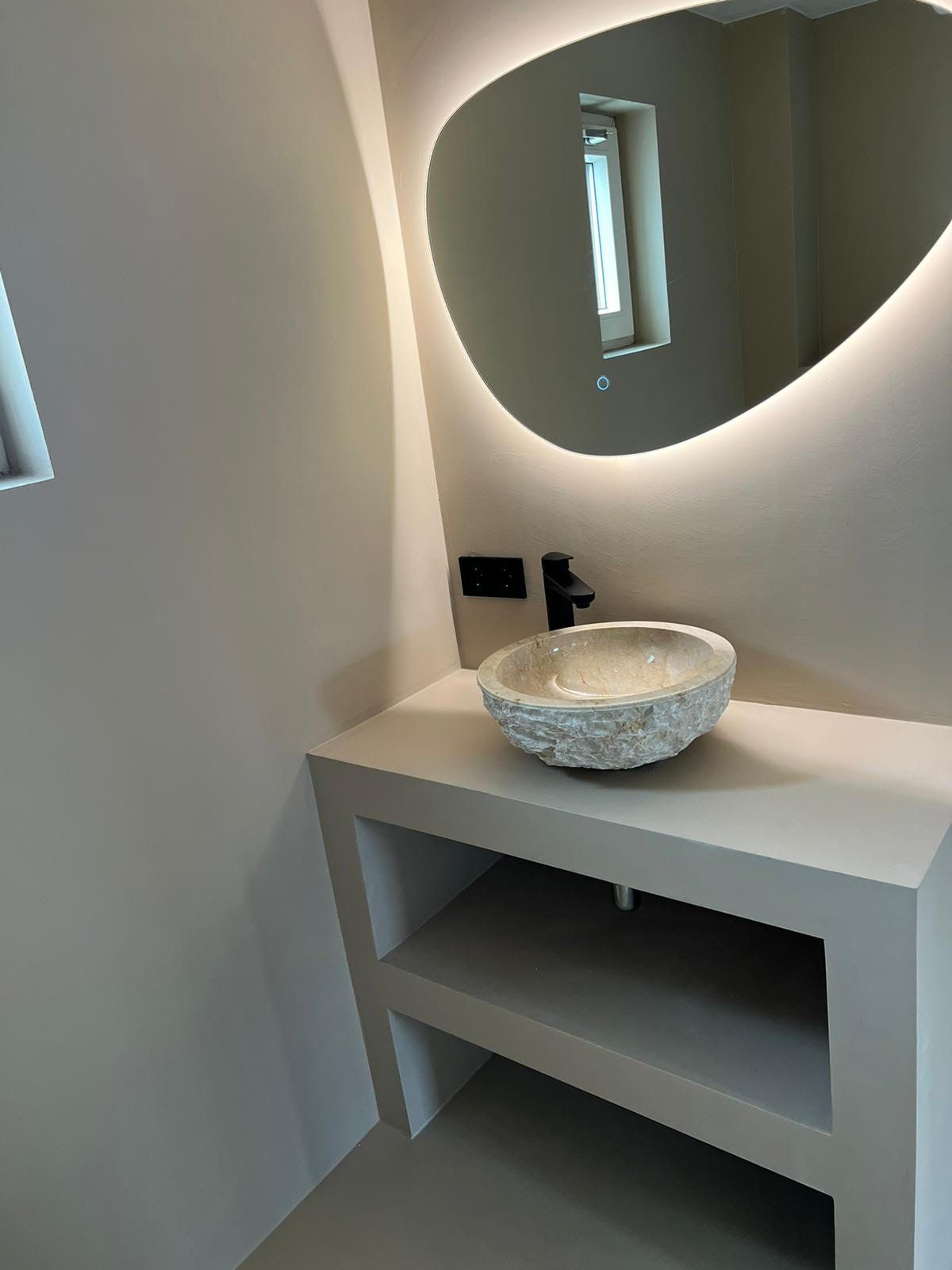 Moderne badkamerkast met ovale spiegel, witte waskom en zachte ledverlichting.