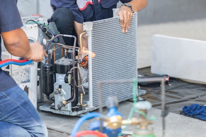 Technicians reviewing digital data near commercial HVAC equipment.