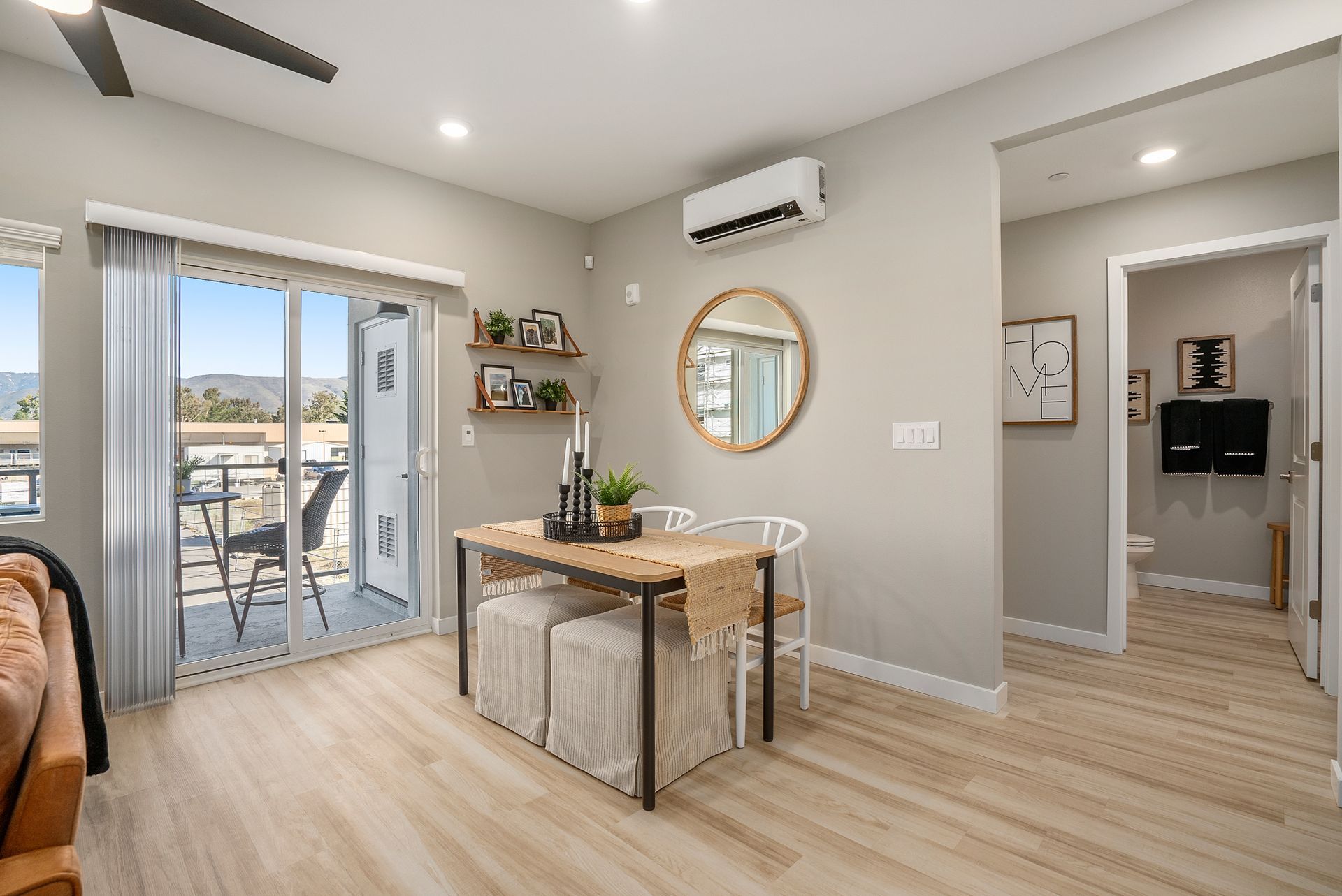 Living room with dining table, sliding door to balcony, light walls and wood floors.