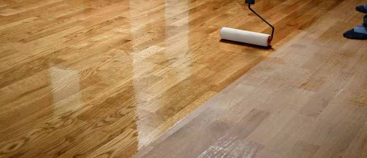 Las manos de una persona instalando paneles de piso laminado de madera de color marrón oscuro 