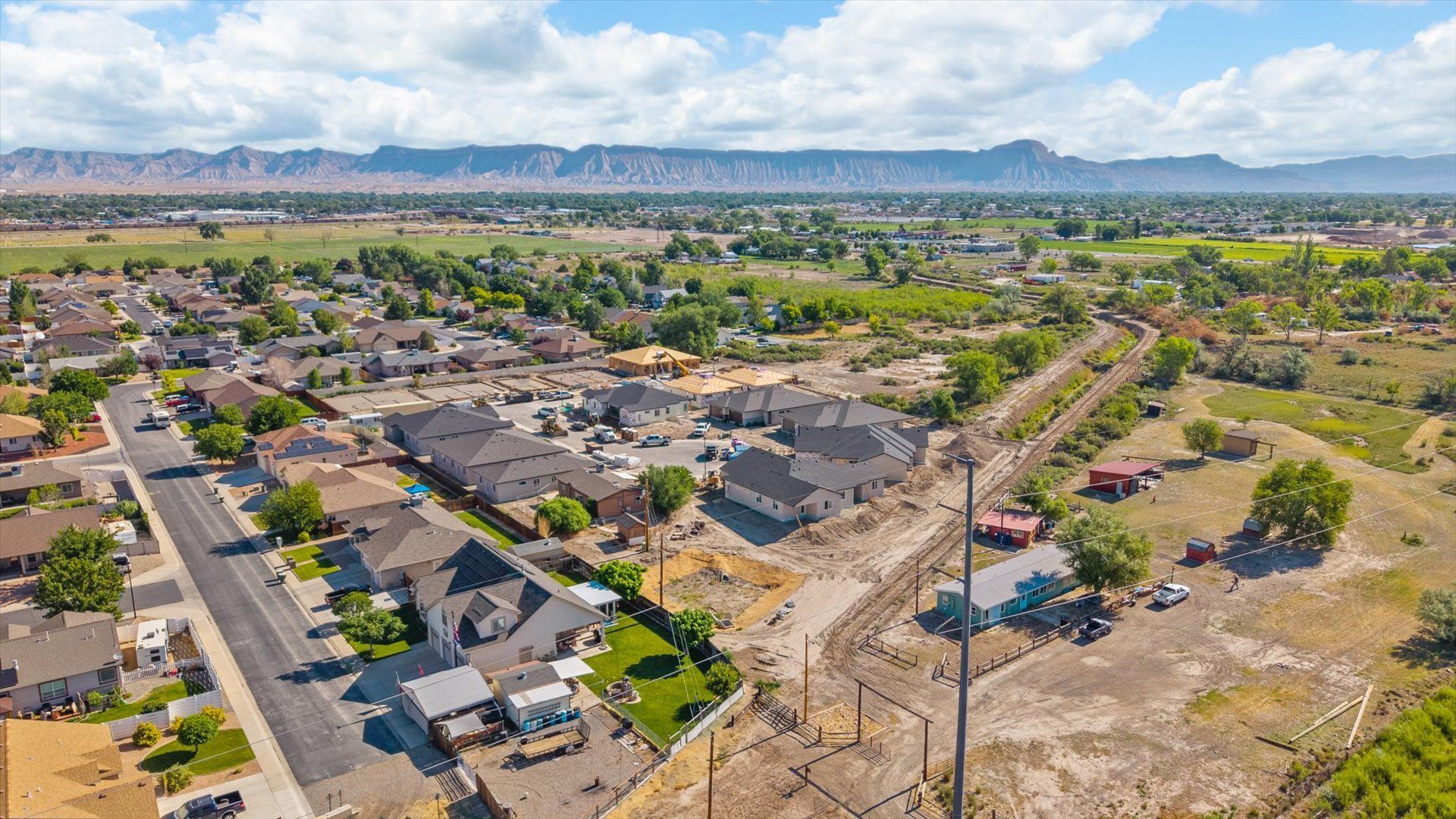 Aerial view of a suburban neighborhood with houses, roads, and distant mountains under a clear sky.
