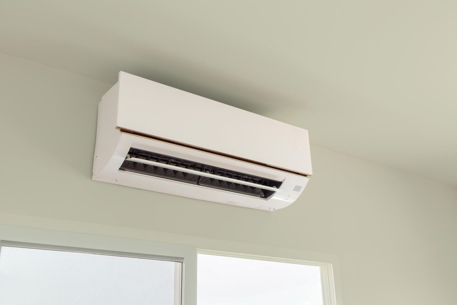 White wall-mounted air conditioner above windows in a bright room