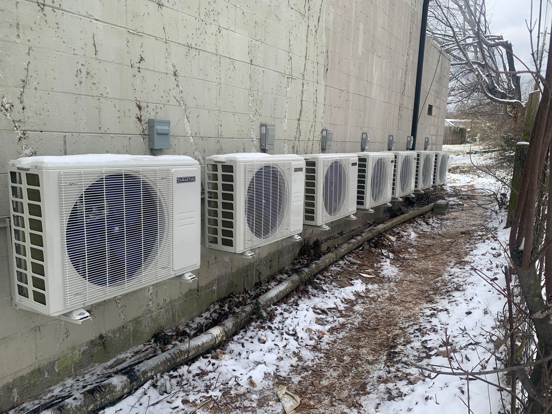 A row of air conditioners are lined up on the side of a building.