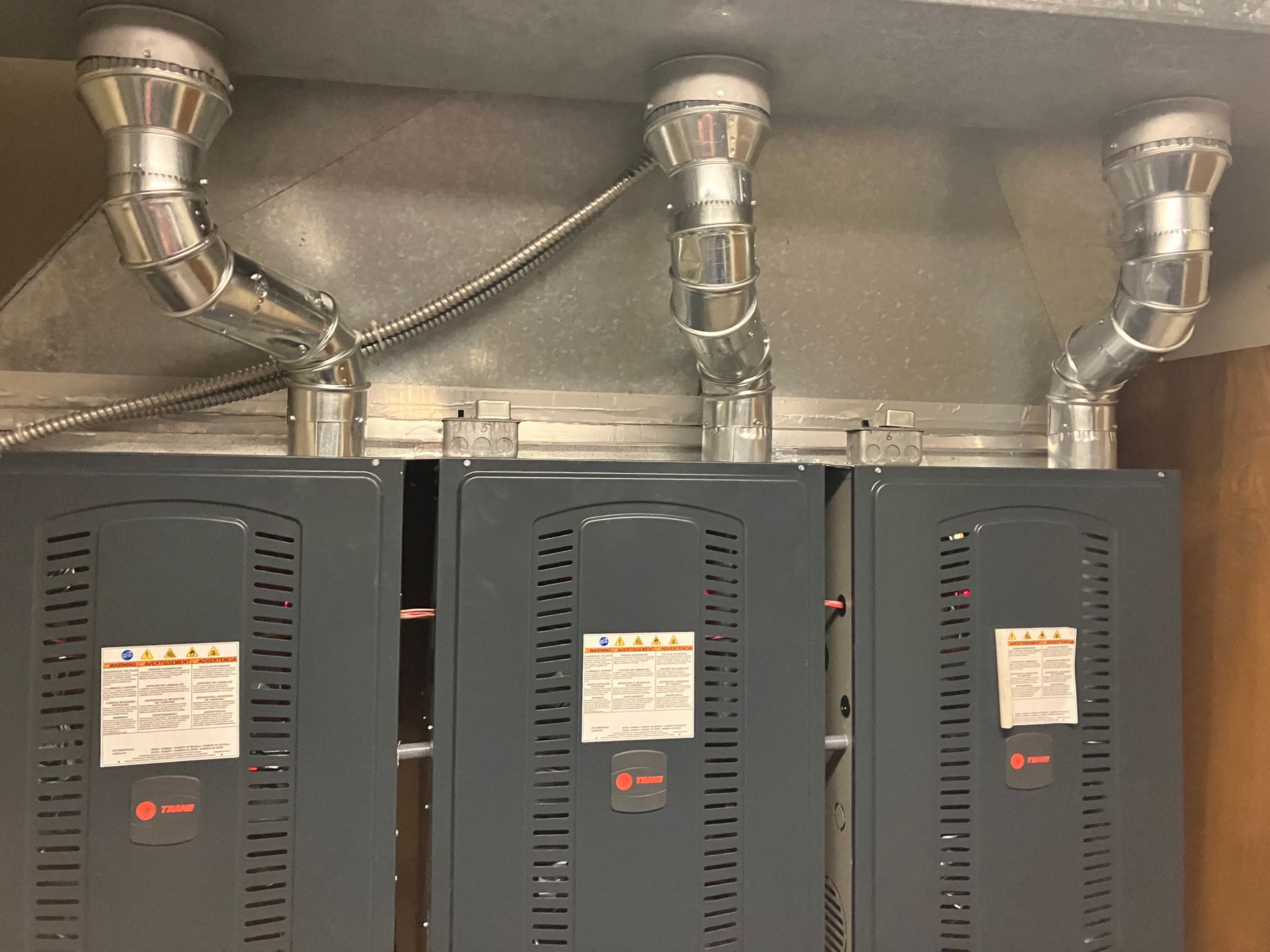 Three water heaters are hanging from the ceiling in a room.