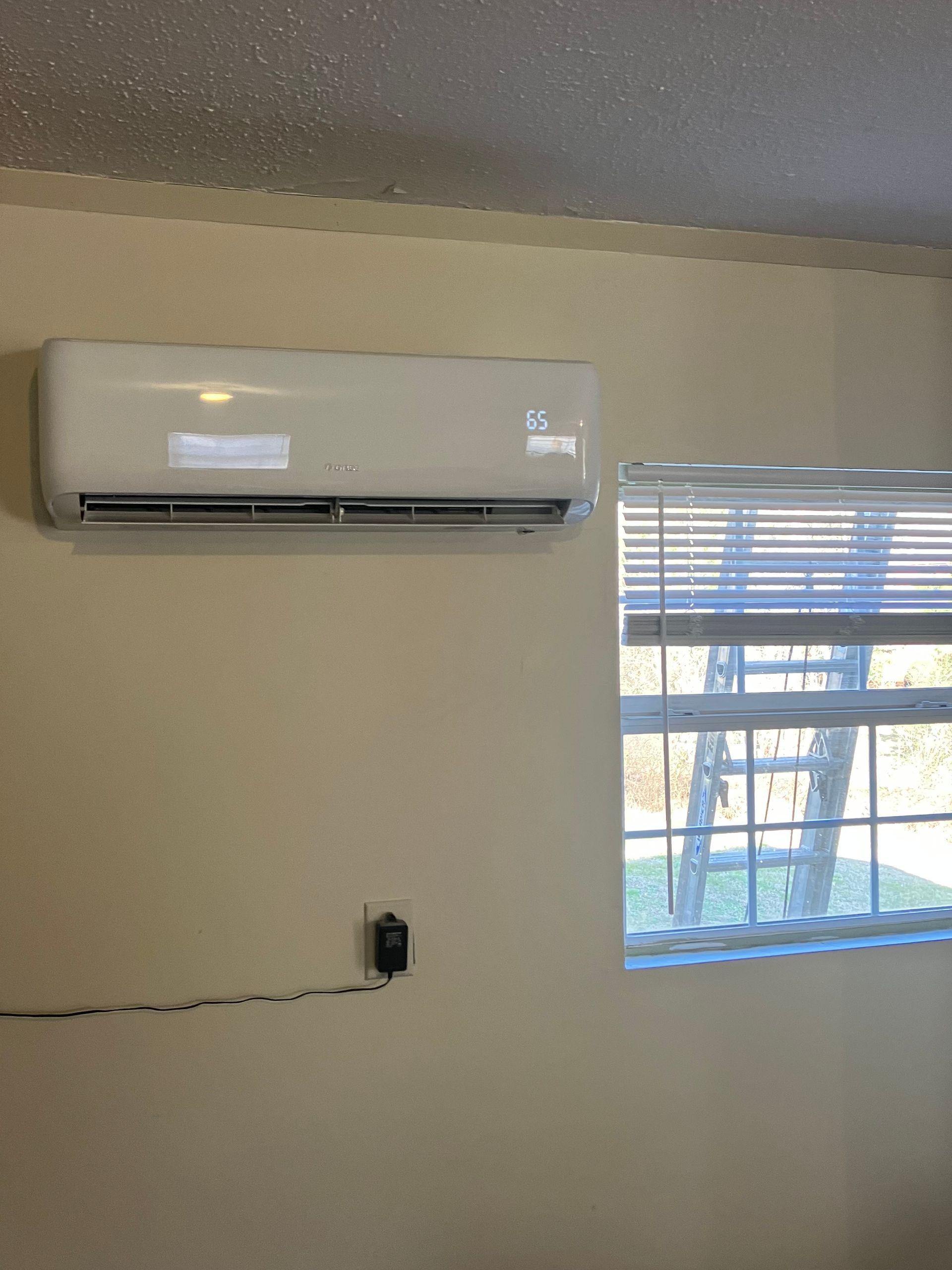A room with a window and a wall mounted air conditioner.