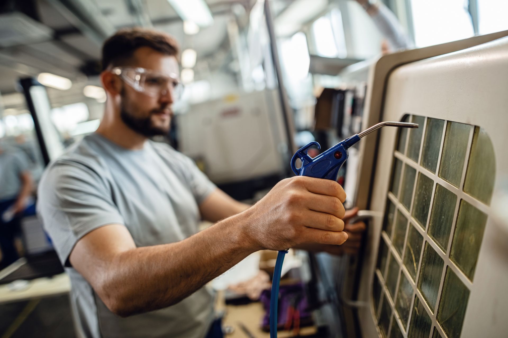 A man is blowing air into a machine in a factory.