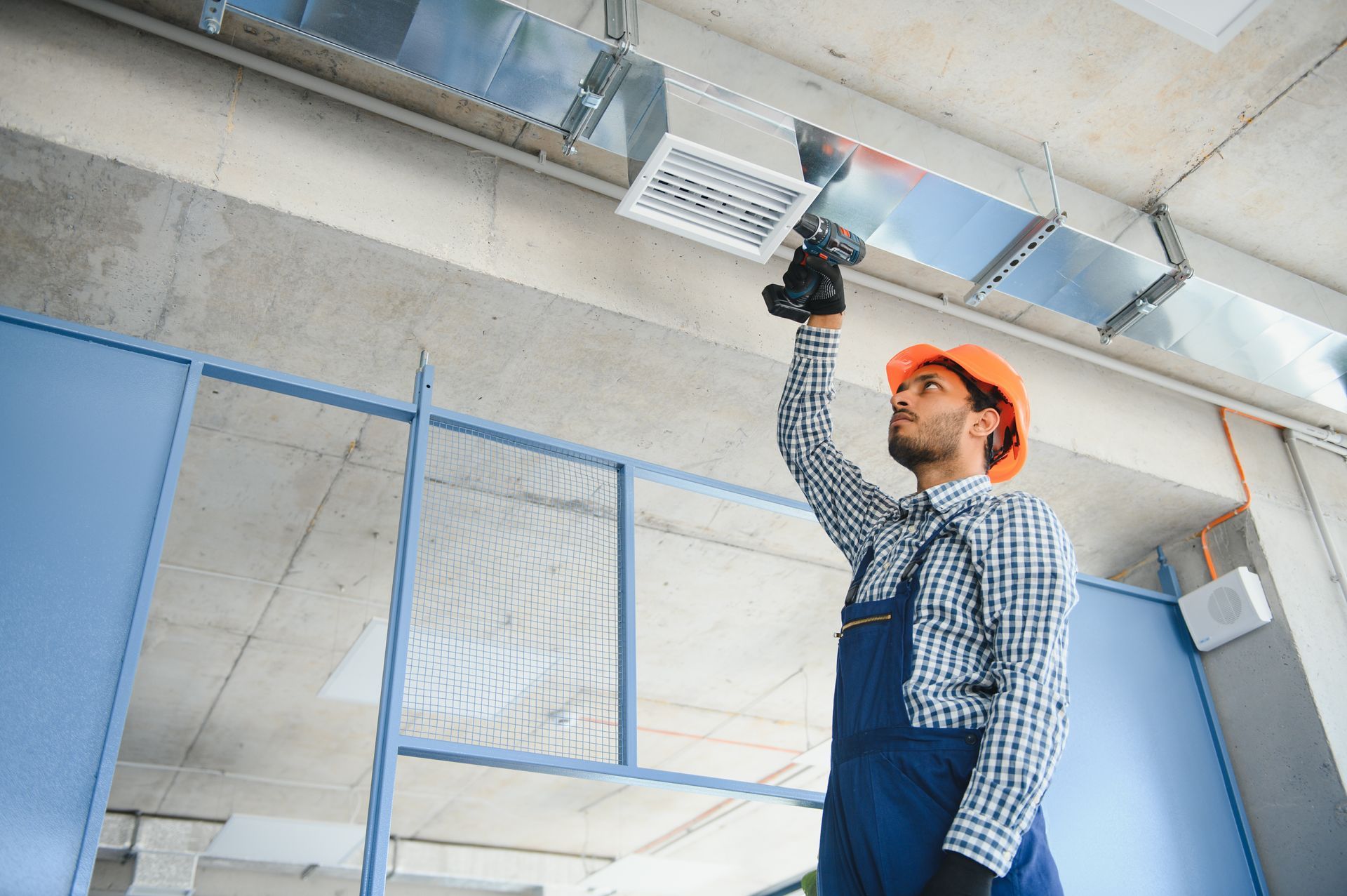 A man is working on a ventilation system in a building.