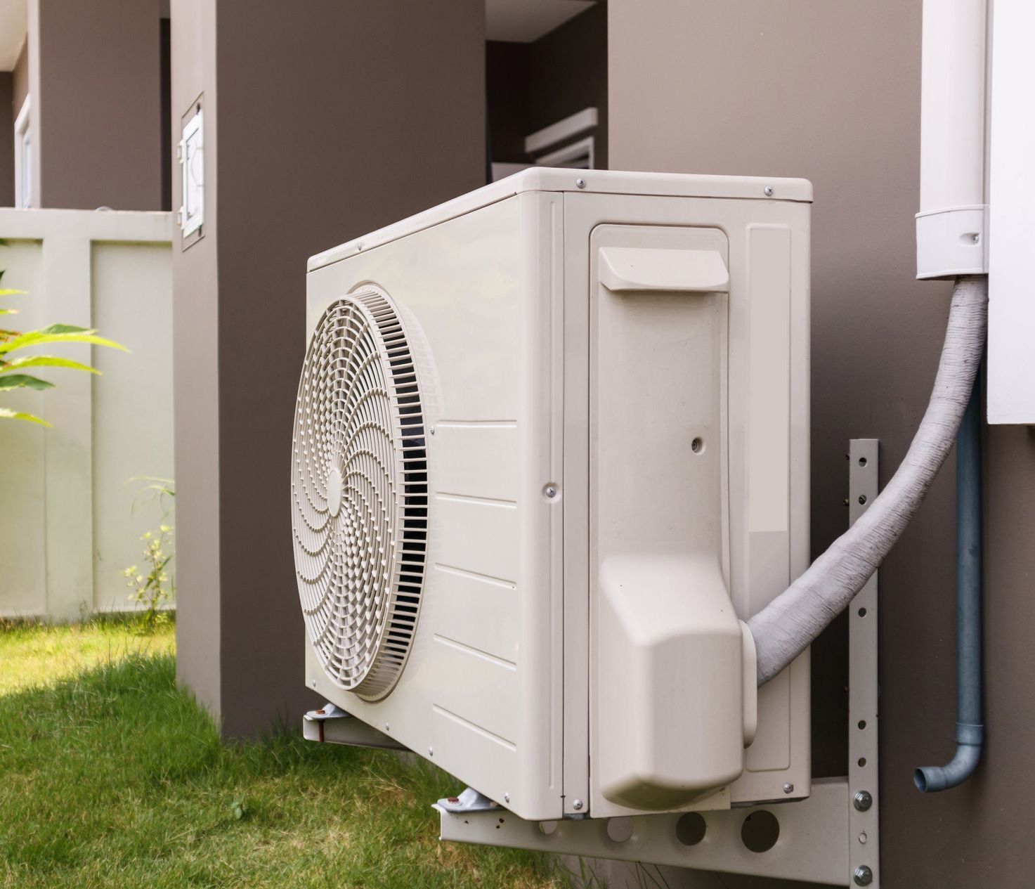 A white air conditioner is mounted on the side of a building.