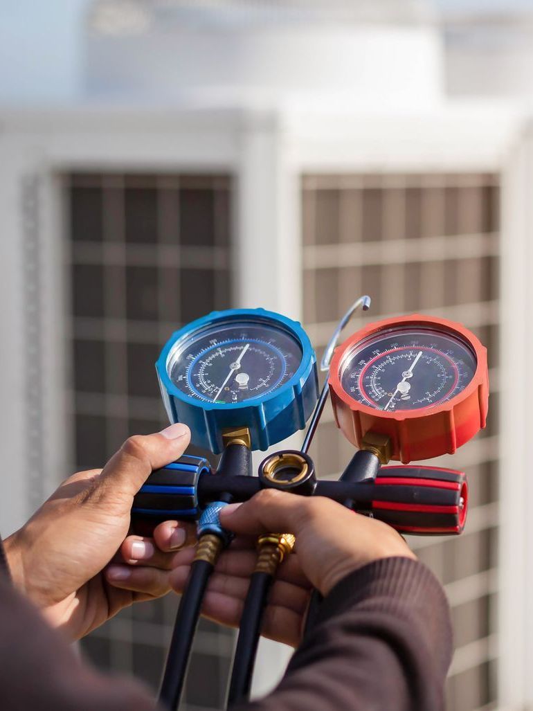 A person is holding two gauges in their hands in front of a building.