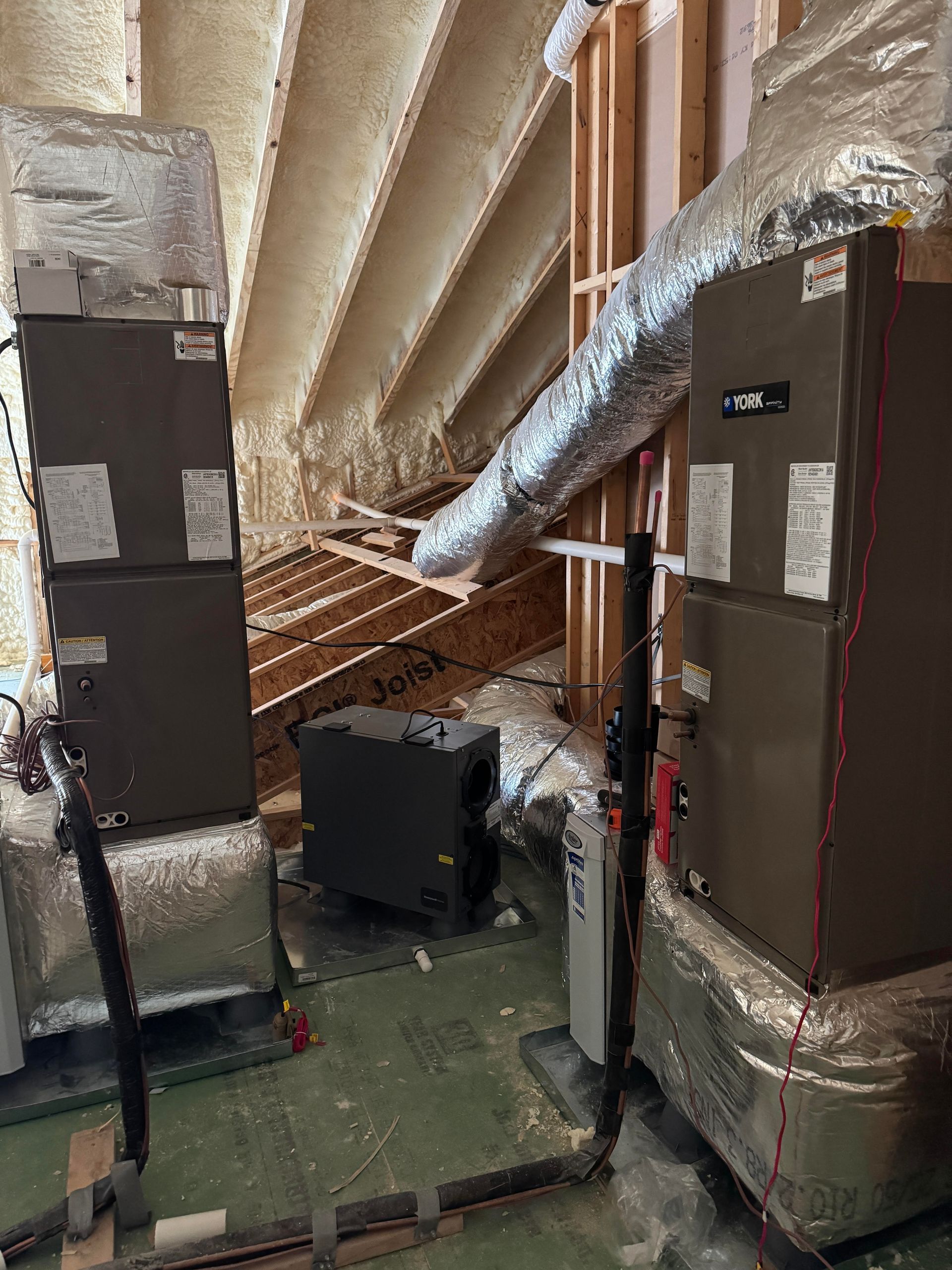 There are two air conditioners in the attic of a house.