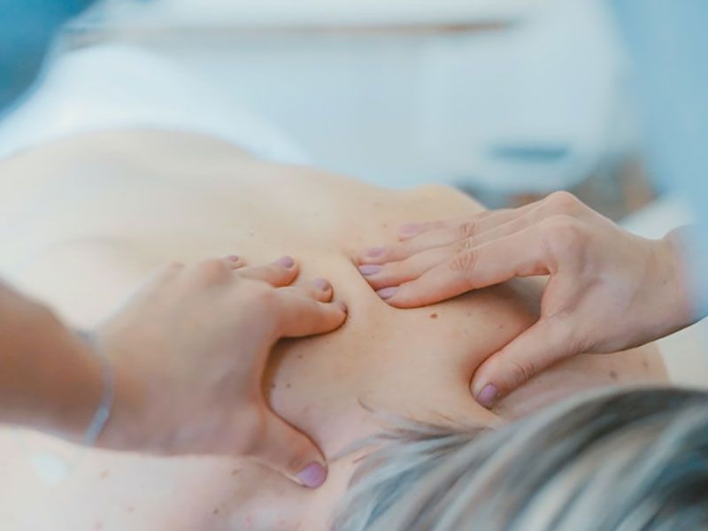 Mãos pressionando as costas nuas de uma pessoa durante uma massagem