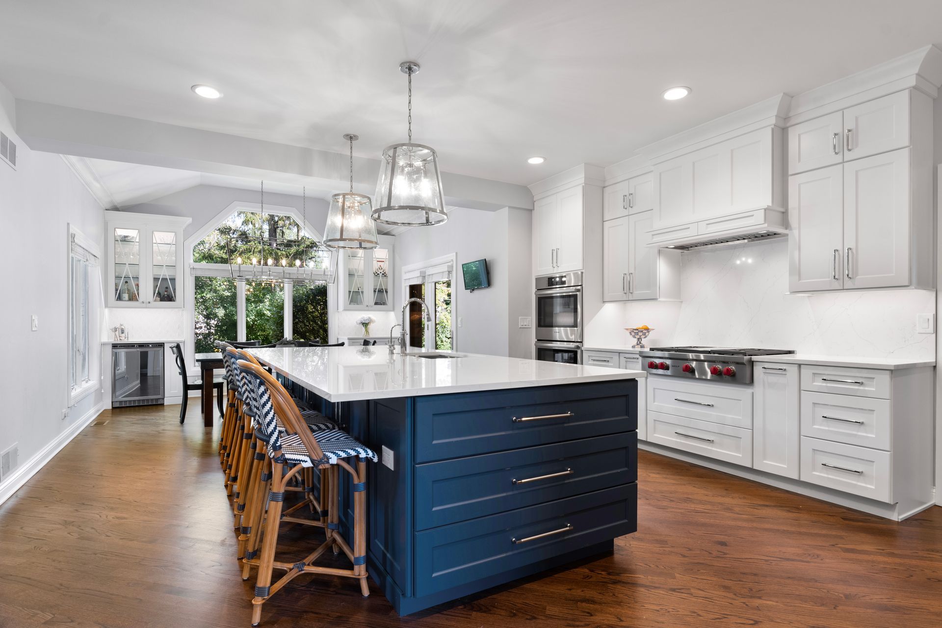 A large kitchen with white cabinets and a blue island.